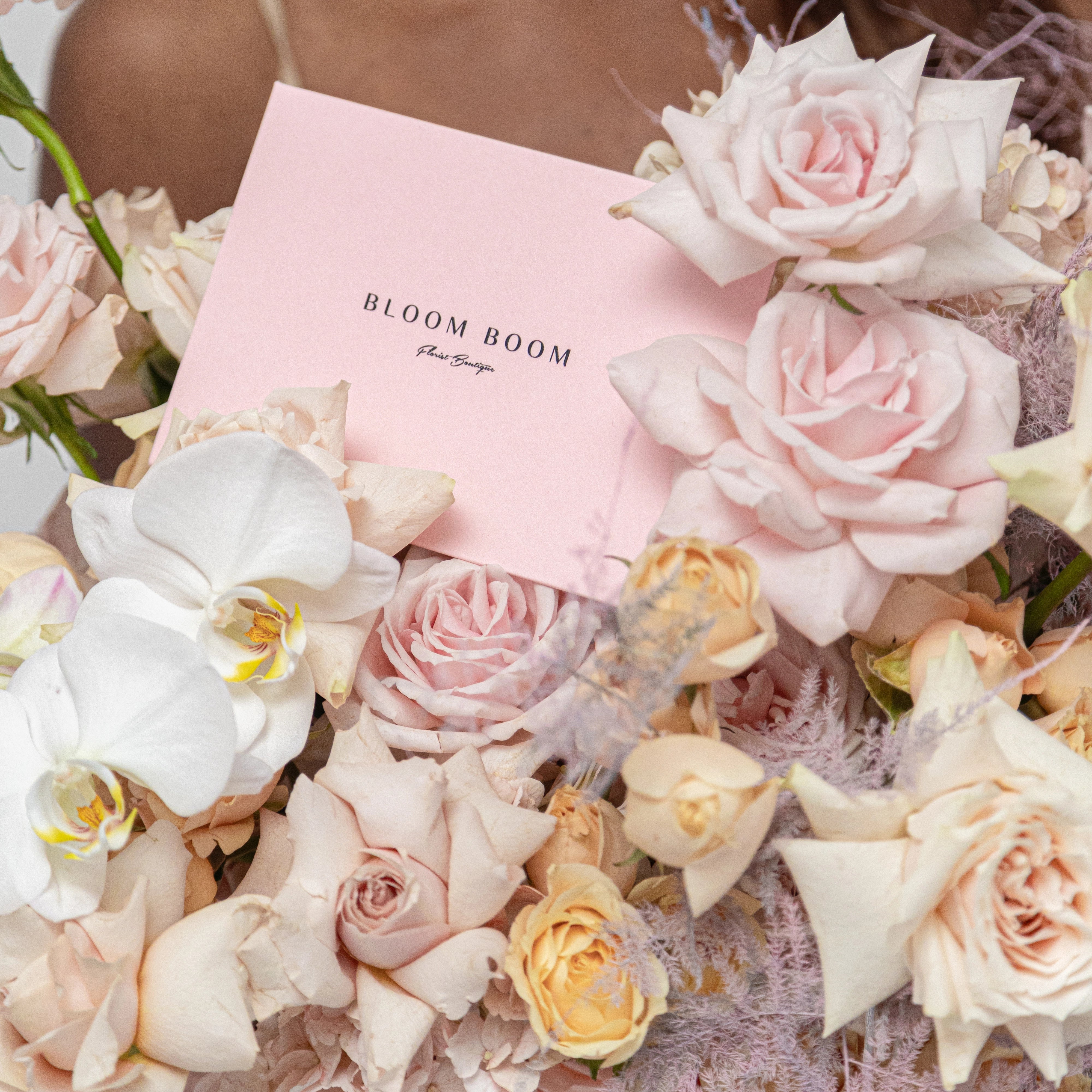 Bloom Boom Flowers luxury gift box with blush pink roses, white orchids, and peach roses in romantic arrangement