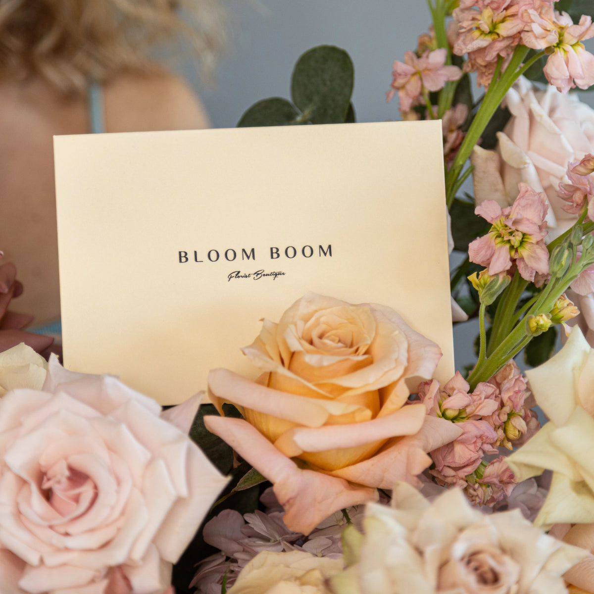 Cream Bloom Boom flower boutique card nestled in pastel pink roses and mixed flowers arrangement