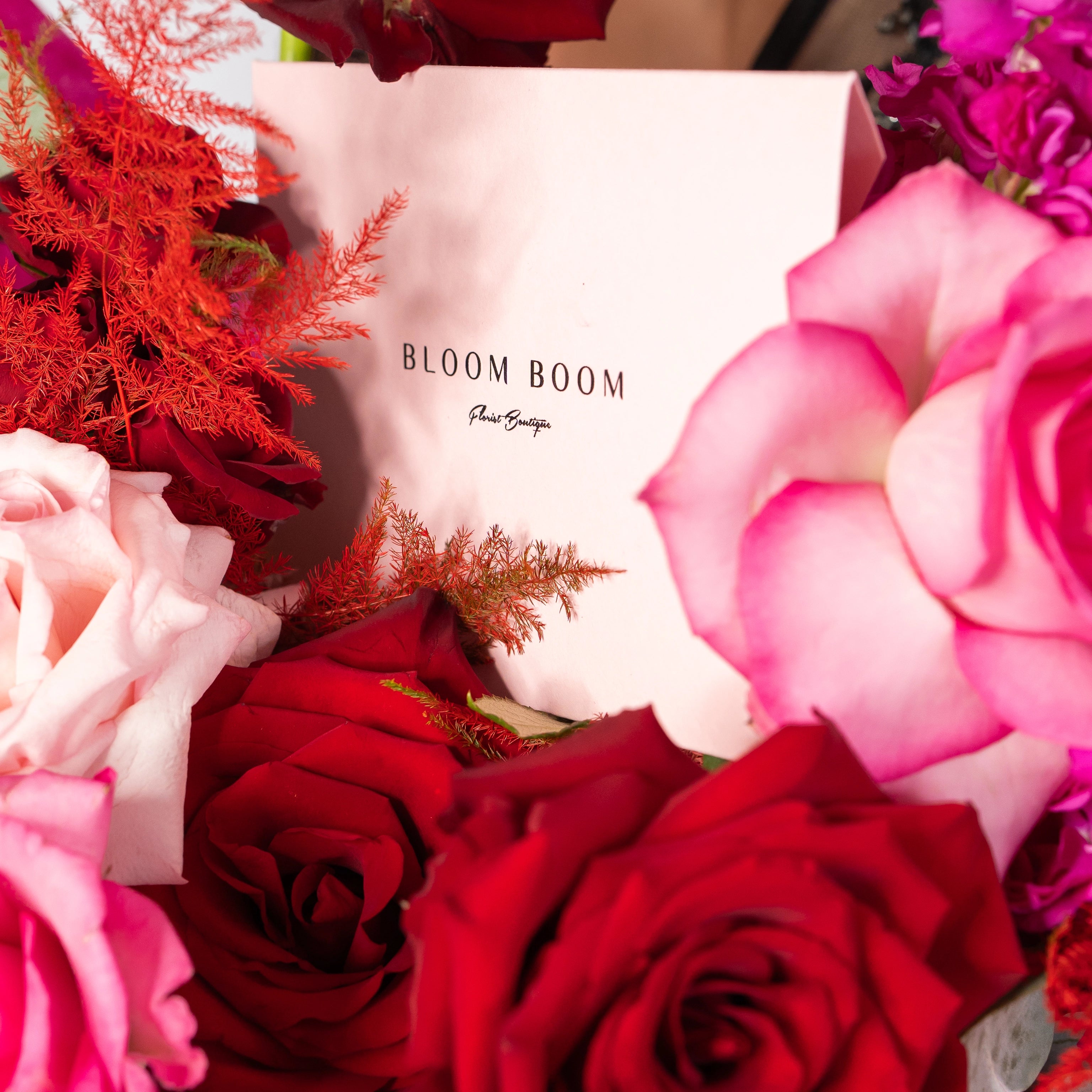 Bloom Boom Flower Boutique business card with red roses, pink roses, and coral dried flowers arrangement