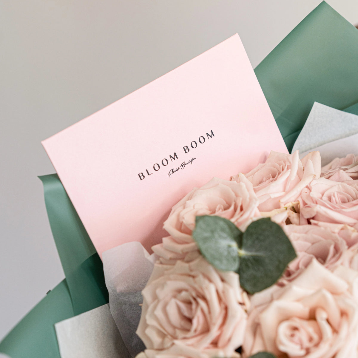 Bloom Boom pink rose bouquet with eucalyptus wrapped in sage green paper and branded pink card