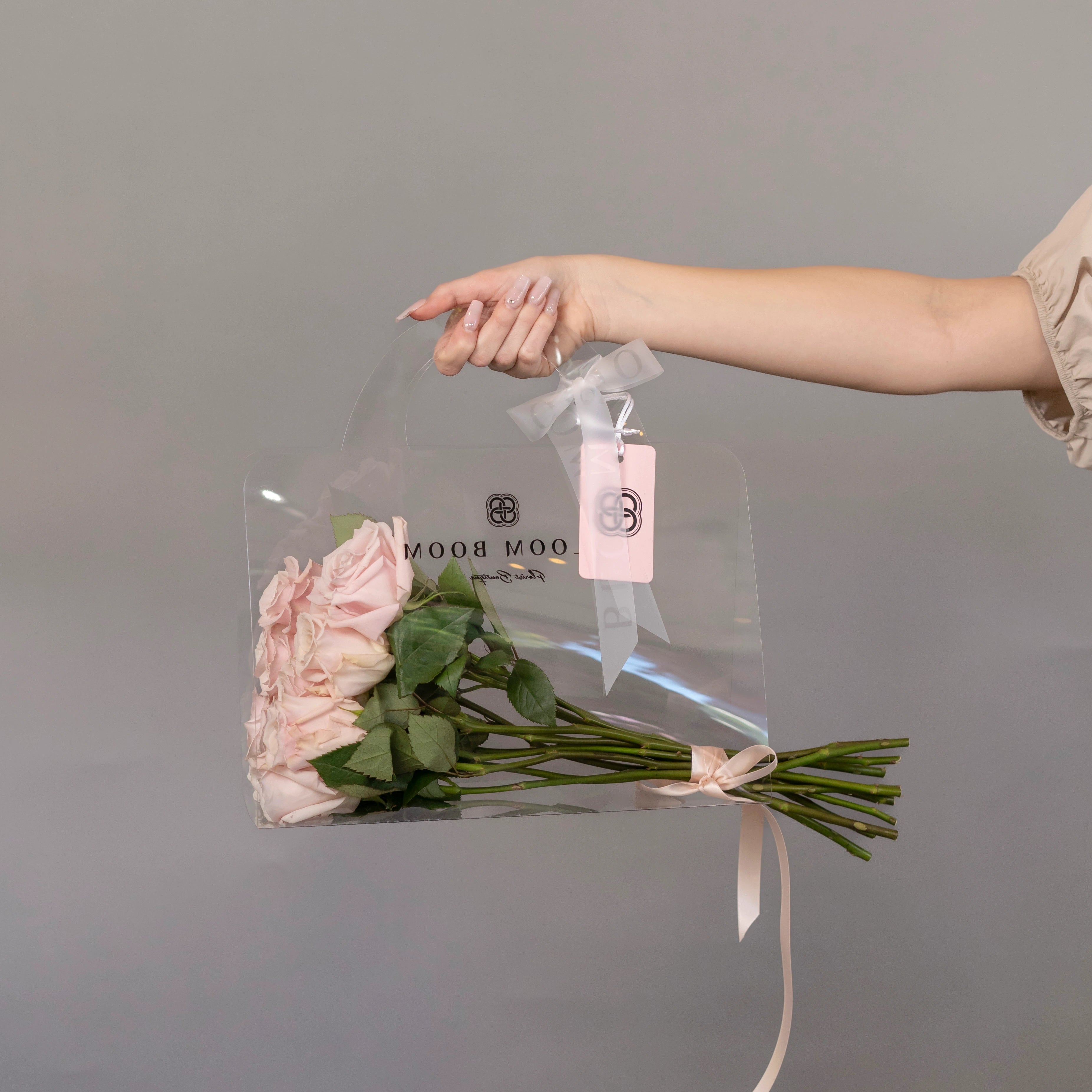 Blush pink roses in clear acrylic gift bag with gray ribbon and pink tag - luxury flower delivery Los Angeles