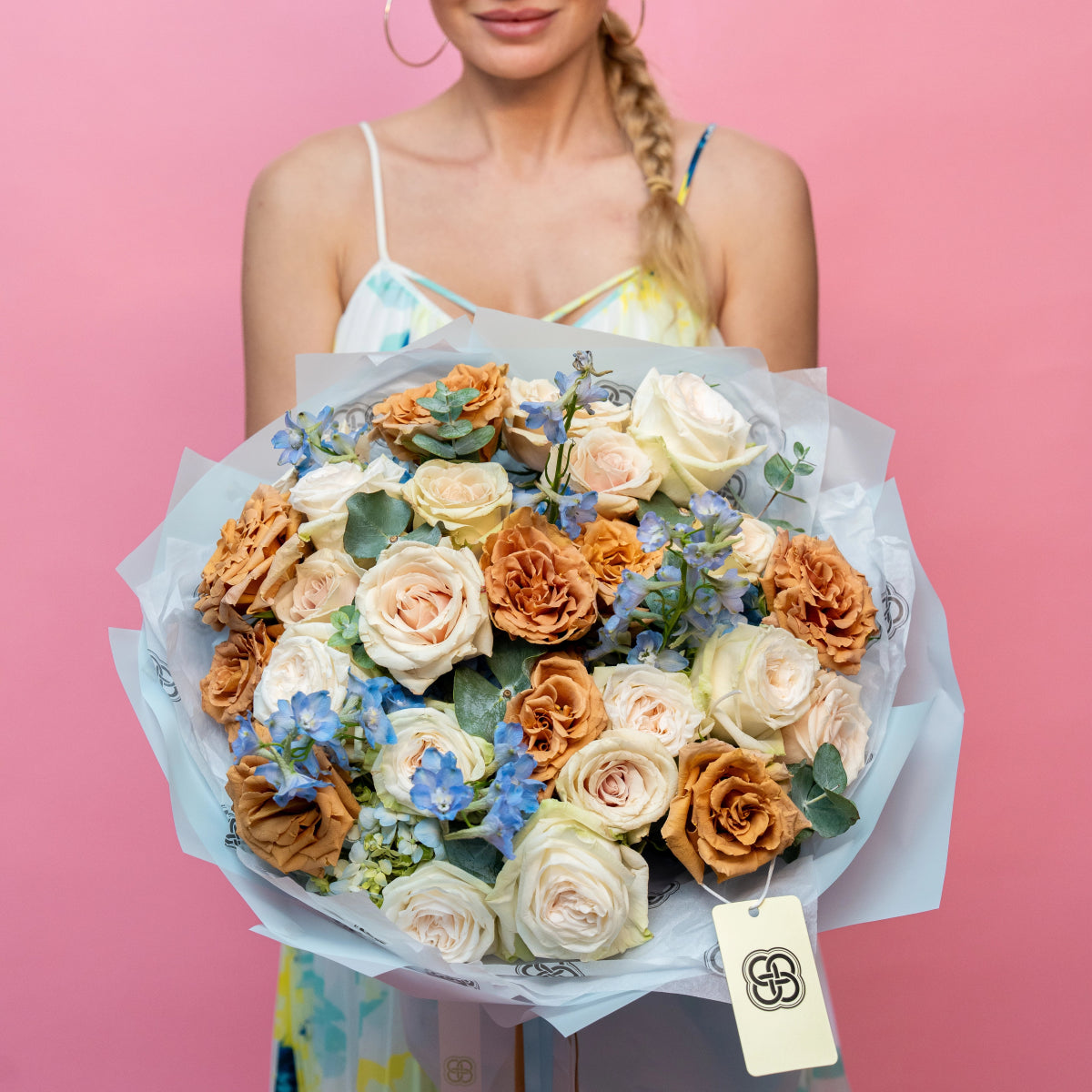 Mixed bouquet with peach roses, white roses, blue delphinium flowers and eucalyptus wrapped in light blue paper