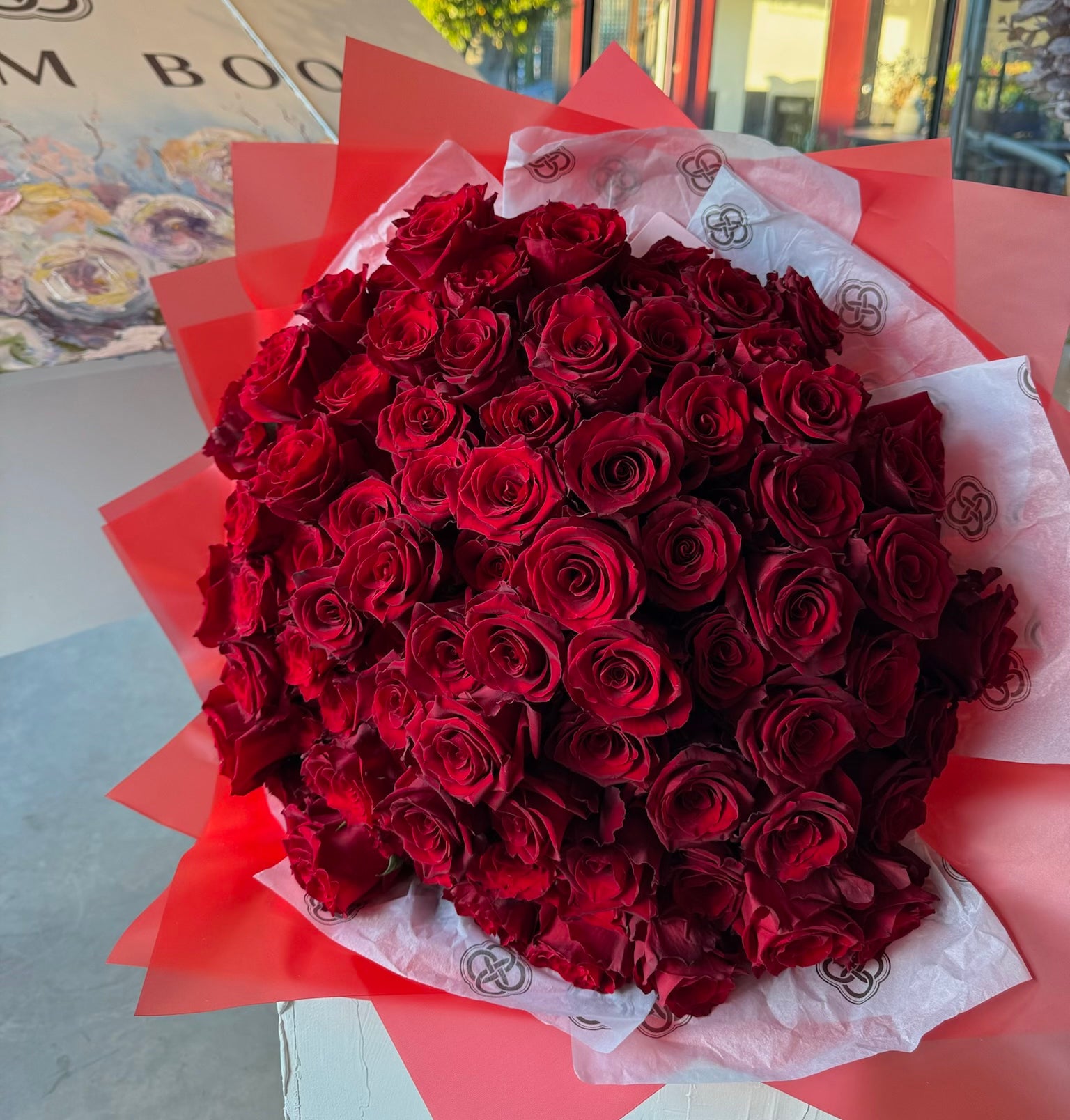 Deep red burgundy rose bouquet wrapped in white tissue and red paper for romantic gifts and special occasions