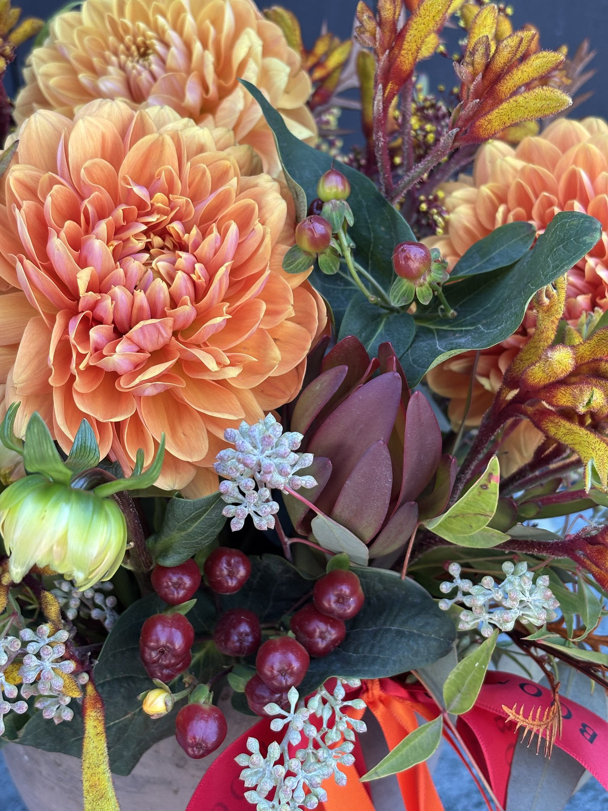 Close-up of Ember Blooms showing apricot dahlias, garnet hypericum berries, leucadendron and golden kangaroo paw