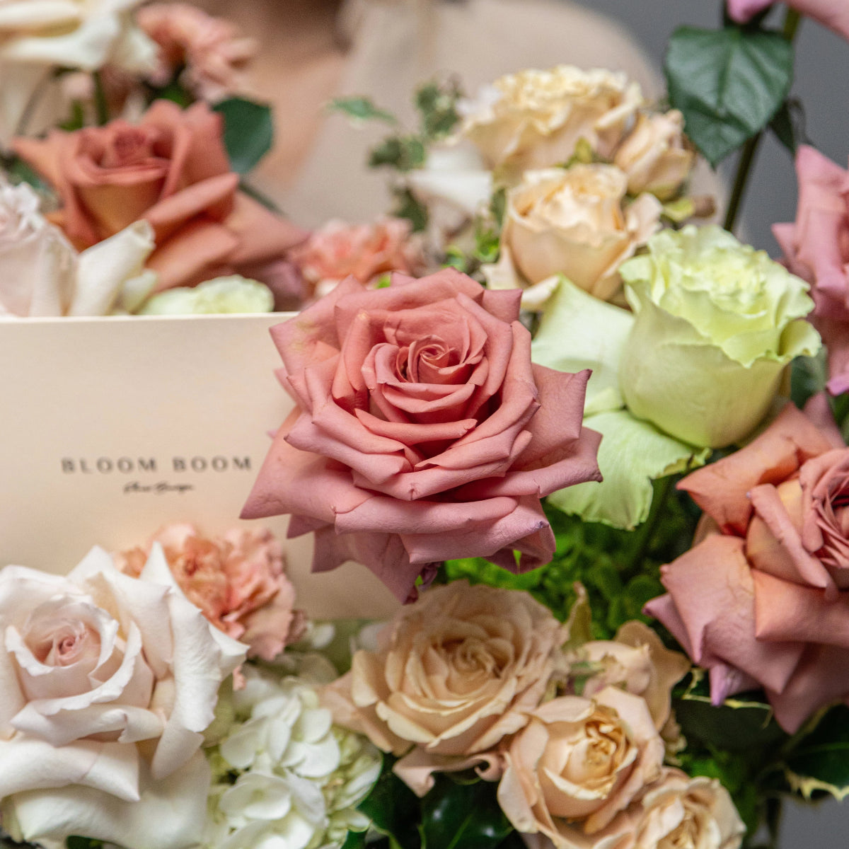 Mixed rose bouquet with dusty pink, cream, white and green roses arranged with Bloom Room florist card