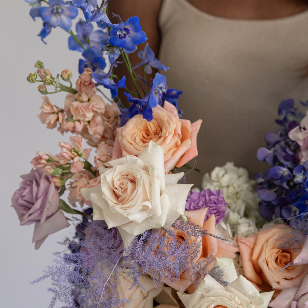 Mixed flower bouquet with peach roses, blue delphinium, purple carnations and lavender dusty miller stems