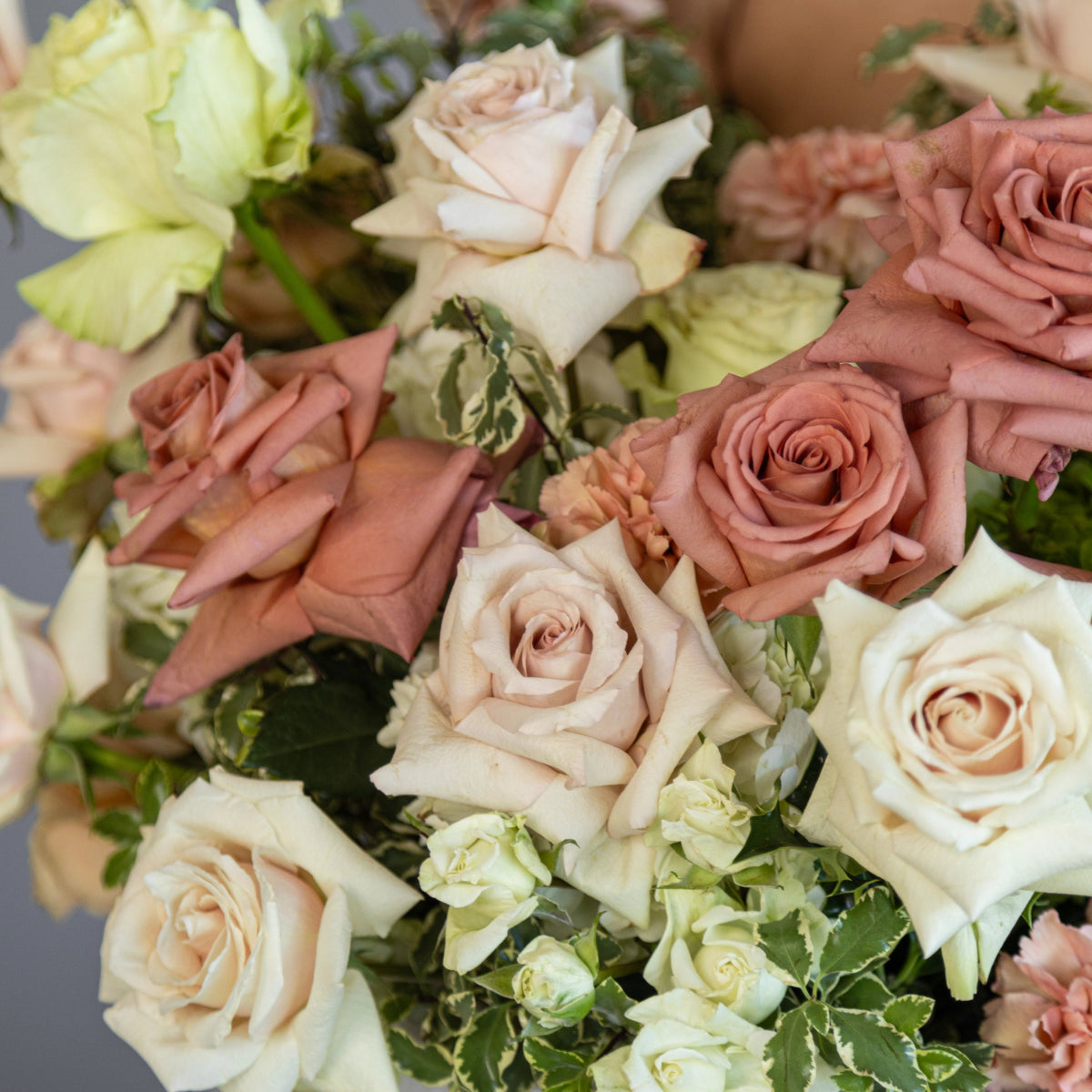 Mixed rose bouquet with blush pink, cream white and coral roses arranged with green foliage and carnations