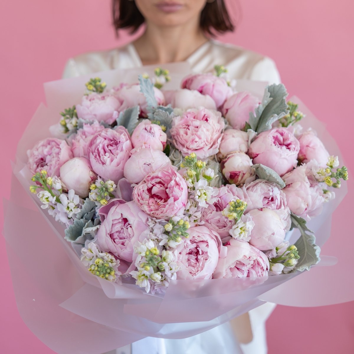 Pink peony bouquet with white stock flowers and dusty miller leaves wrapped in sheer tulle ribbon