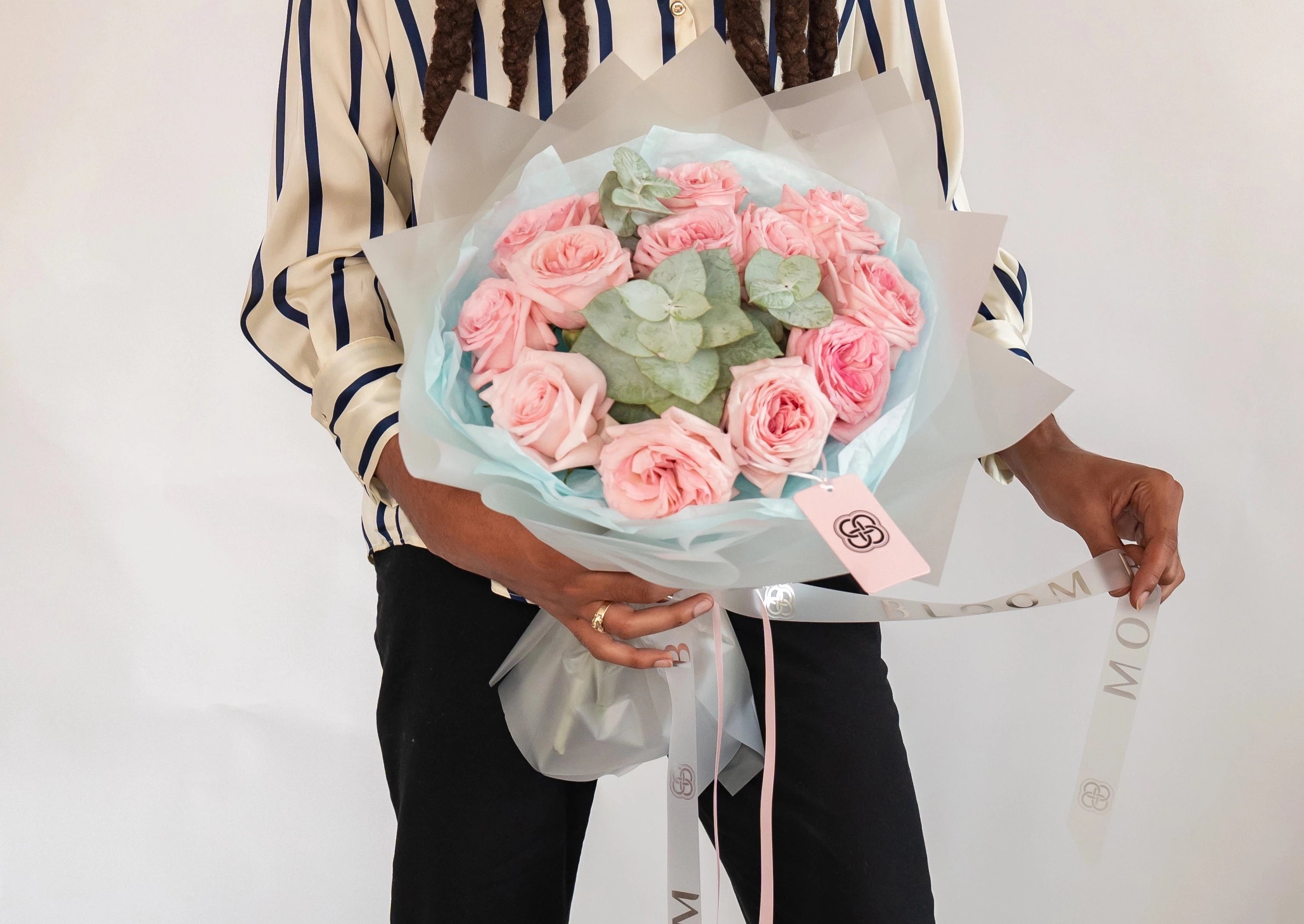 Pink rose bouquet with eucalyptus leaves wrapped in light blue and white paper for flower delivery
