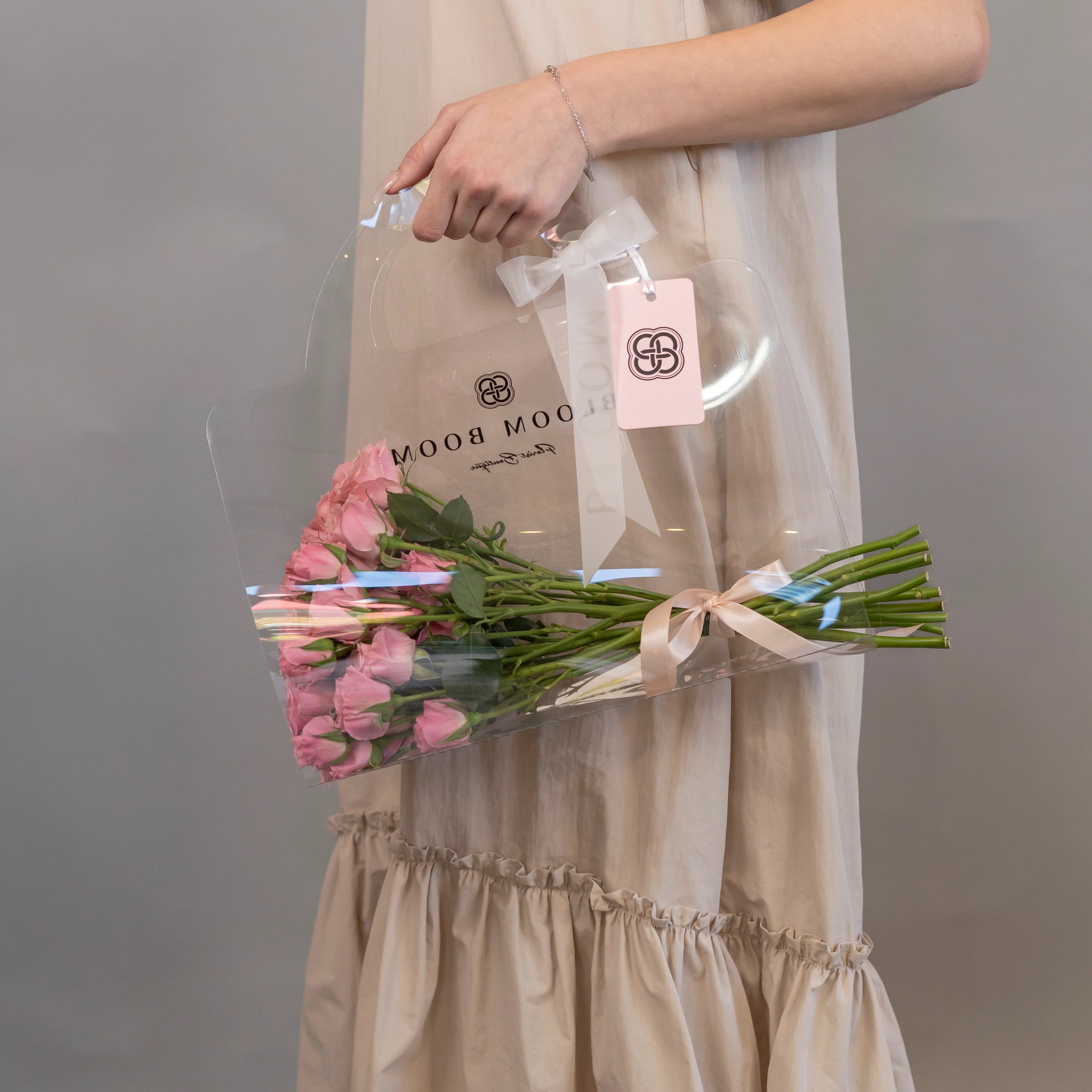 Pink roses bouquet in clear protective sleeve with Bloom Boom Flowers branded bag and gift tag for delivery