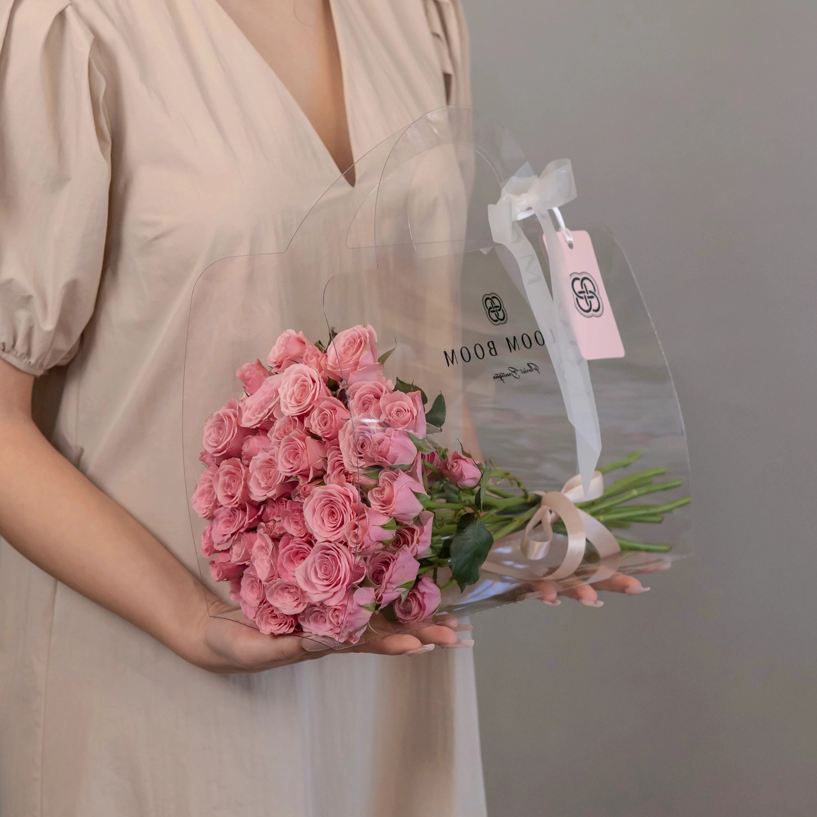 Pink spray roses bouquet wrapped in cellophane with Bloom Boom Los Angeles florist branding and ribbon