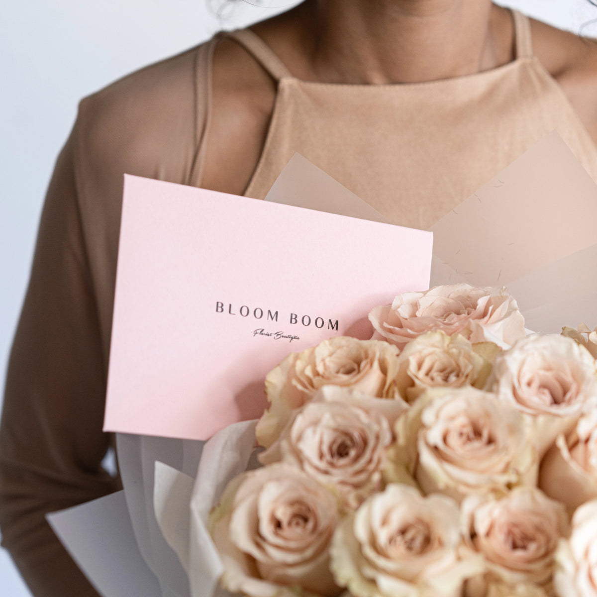 Blush pink quicksand roses bouquet in white wrapper with pink Bloom Boom flower boutique card