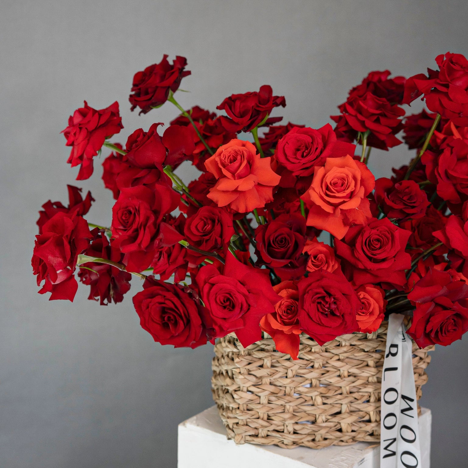 Red and coral roses in wicker basket arrangement for delivery in Los Angeles by Bloom Boom Flowers florist