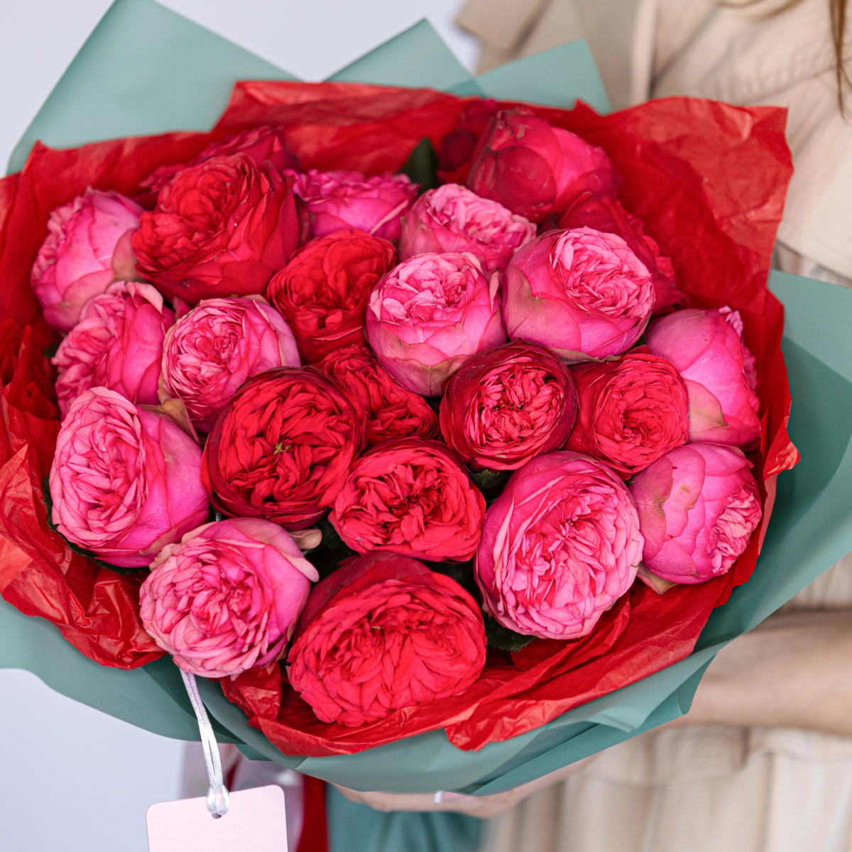 Bouquet of 24 red and pink garden roses wrapped in mint green and red tissue paper with gift tag