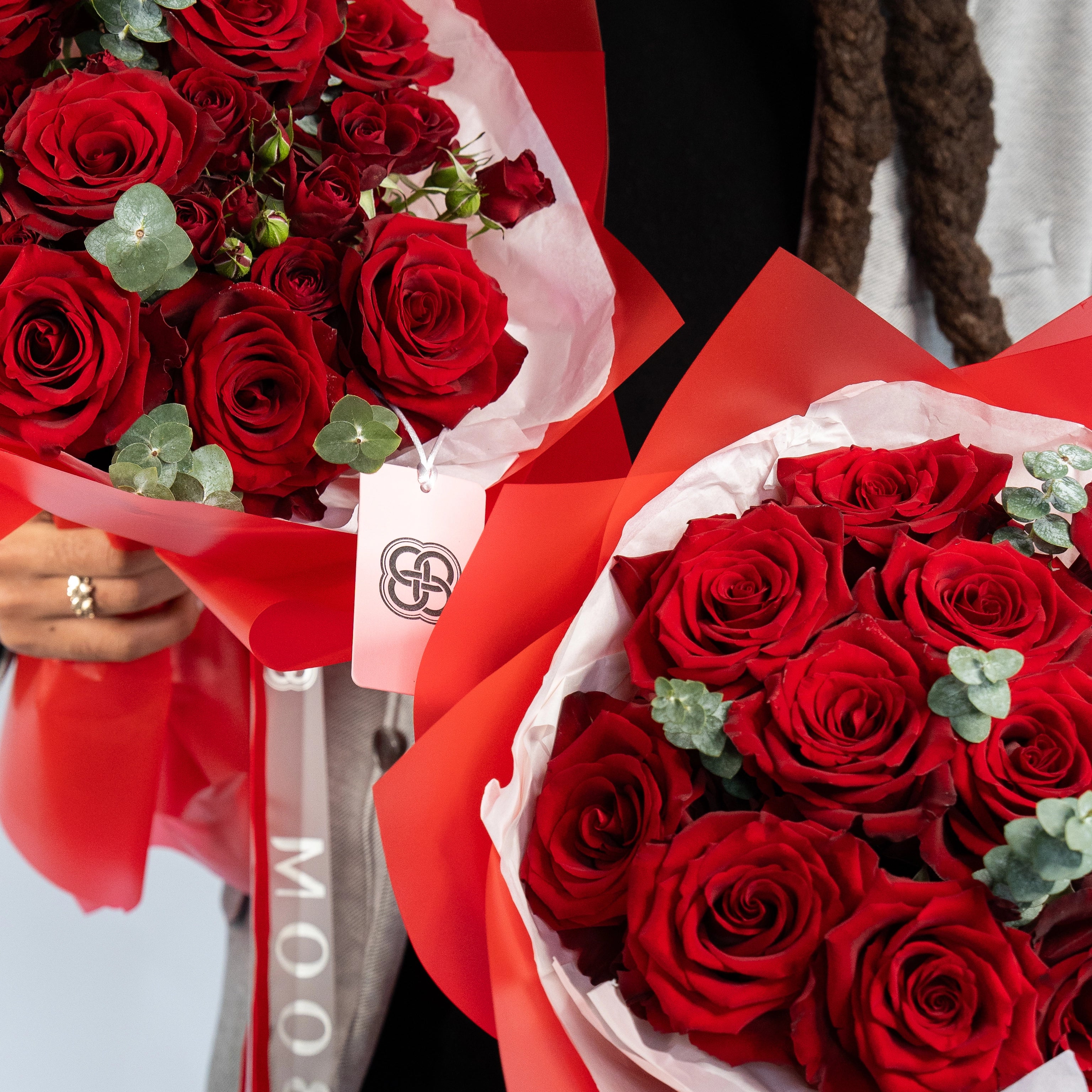 Two red rose bouquets with eucalyptus in red gift wrap and tags, perfect for romantic delivery in Los Angeles