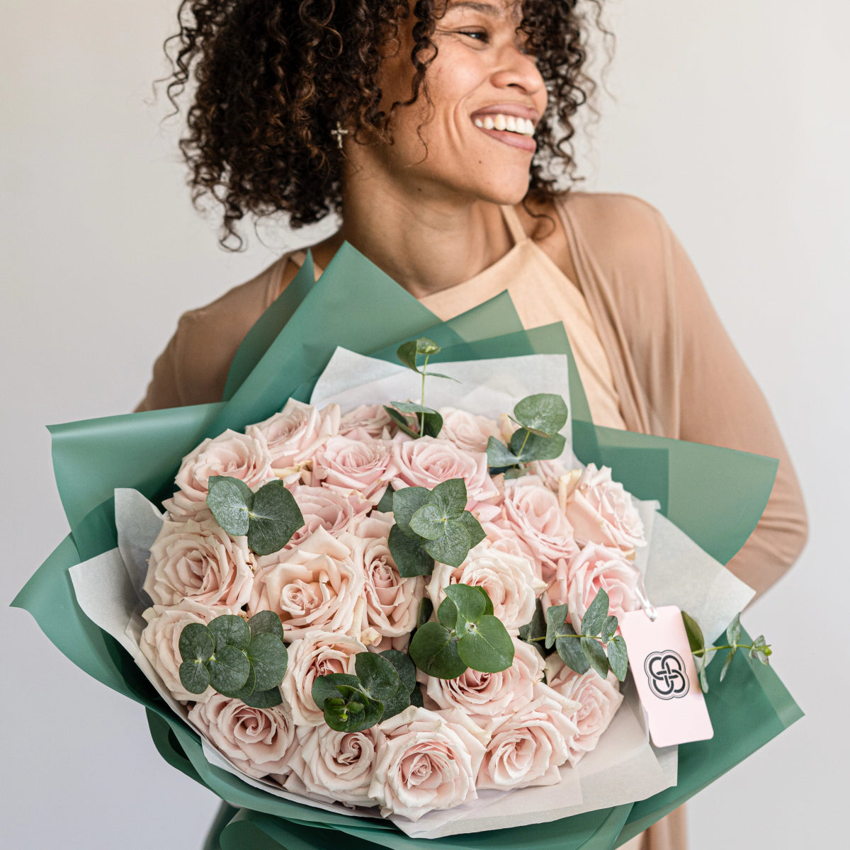 Elegant bouquet of 25 blush pink roses with eucalyptus leaves wrapped in sage green and white paper