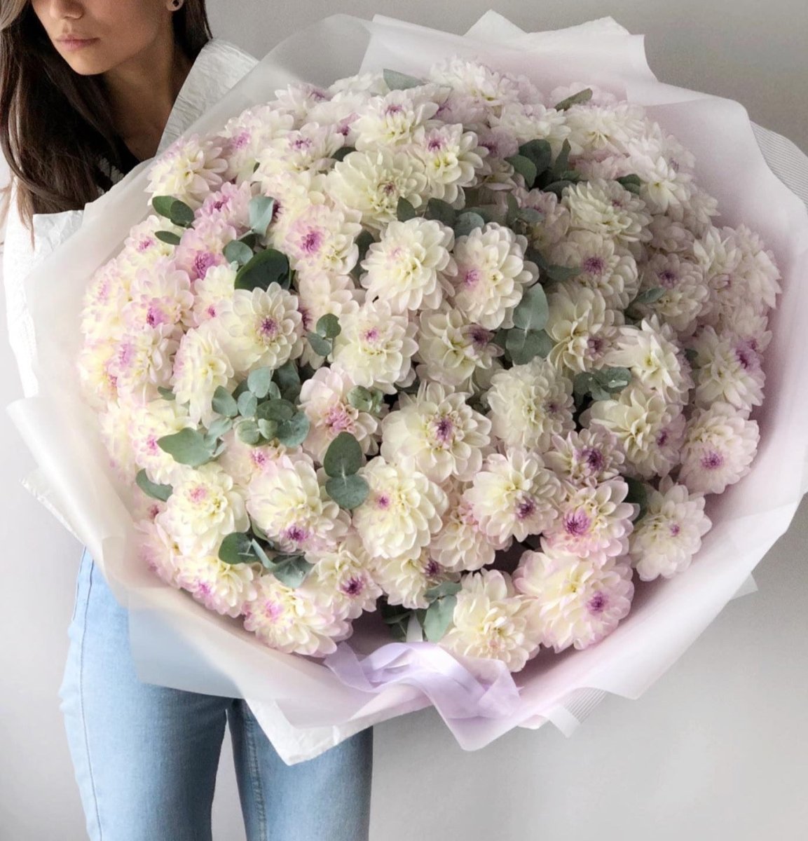 Large bouquet of white and pale pink dahlias with eucalyptus wrapped in white tissue paper with lavender ribbon