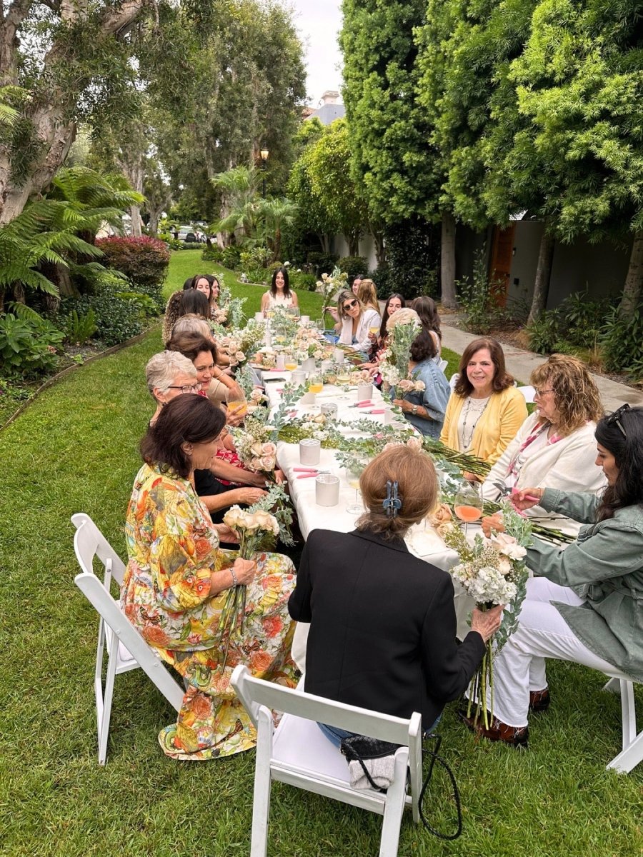 Guests gathered at an outdoor garden table working through pastel arrangements together.