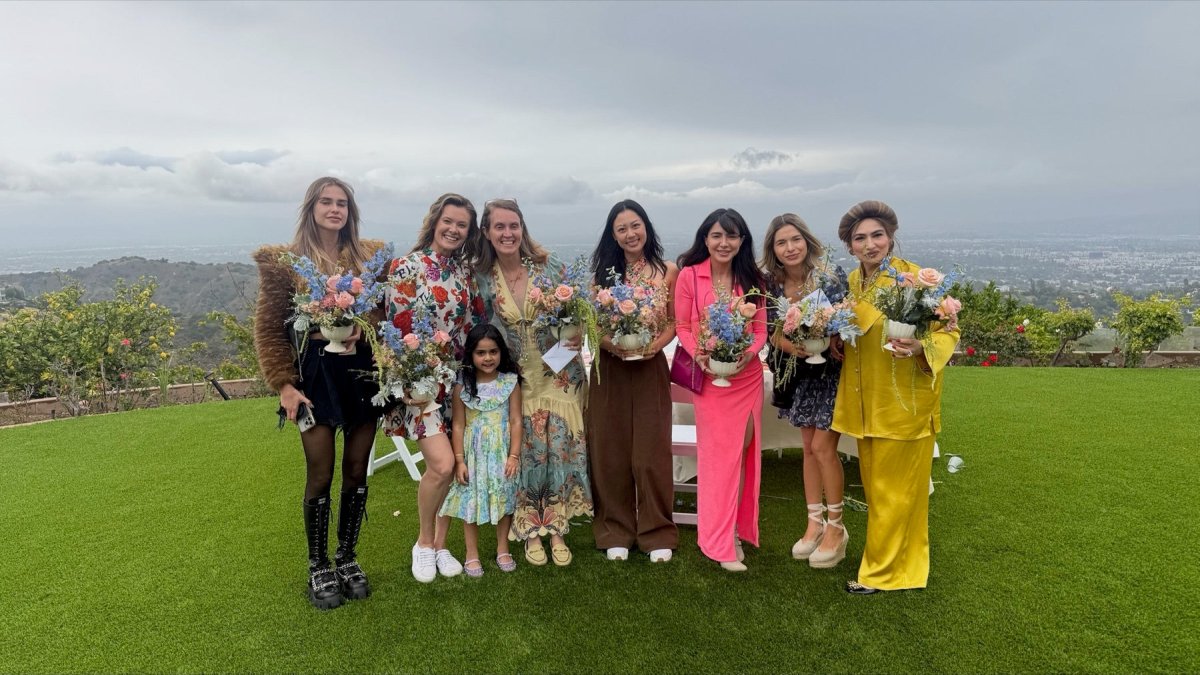 Guests on a hilltop lawn above Los Angeles, each holding a finished pastel flower arrangement.