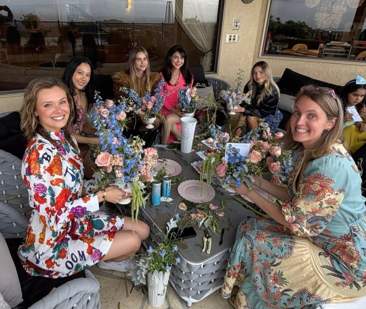 Smiling guests around a patio table at a private home with finished blue and pink arrangements.
