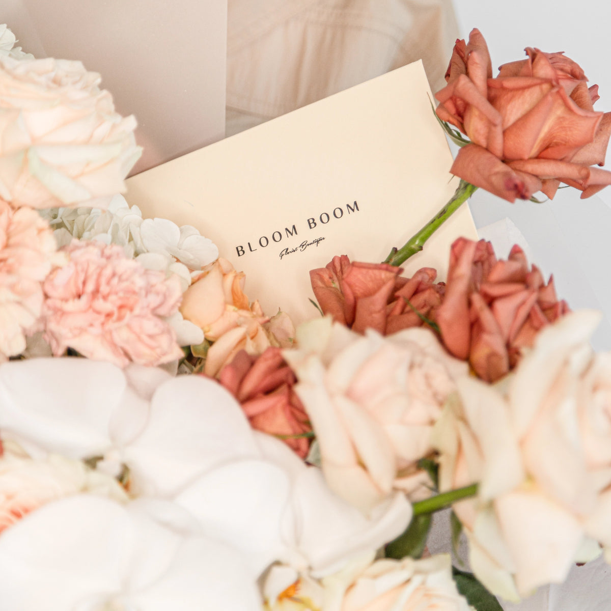 Bloom Boom Caffè Latte bouquet with white hydrangeas, coral roses, and cream peonies arranged with branded card