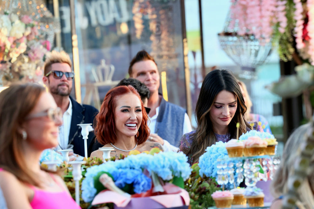 Guests laughing at the dessert table amid blue hydrangeas and cupcake stands
