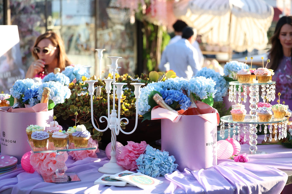 Outdoor dessert table with blue hydrangeas, cupcakes and champagne in Bloom Boom gift bags