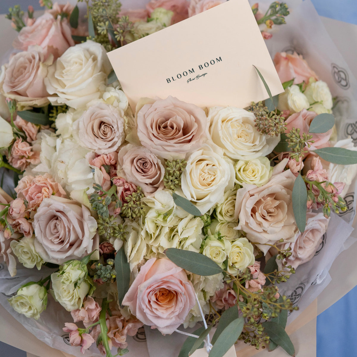 Luxury mixed rose bouquet in blush pink, cream and white tones with eucalyptus leaves and Bloom Boom card