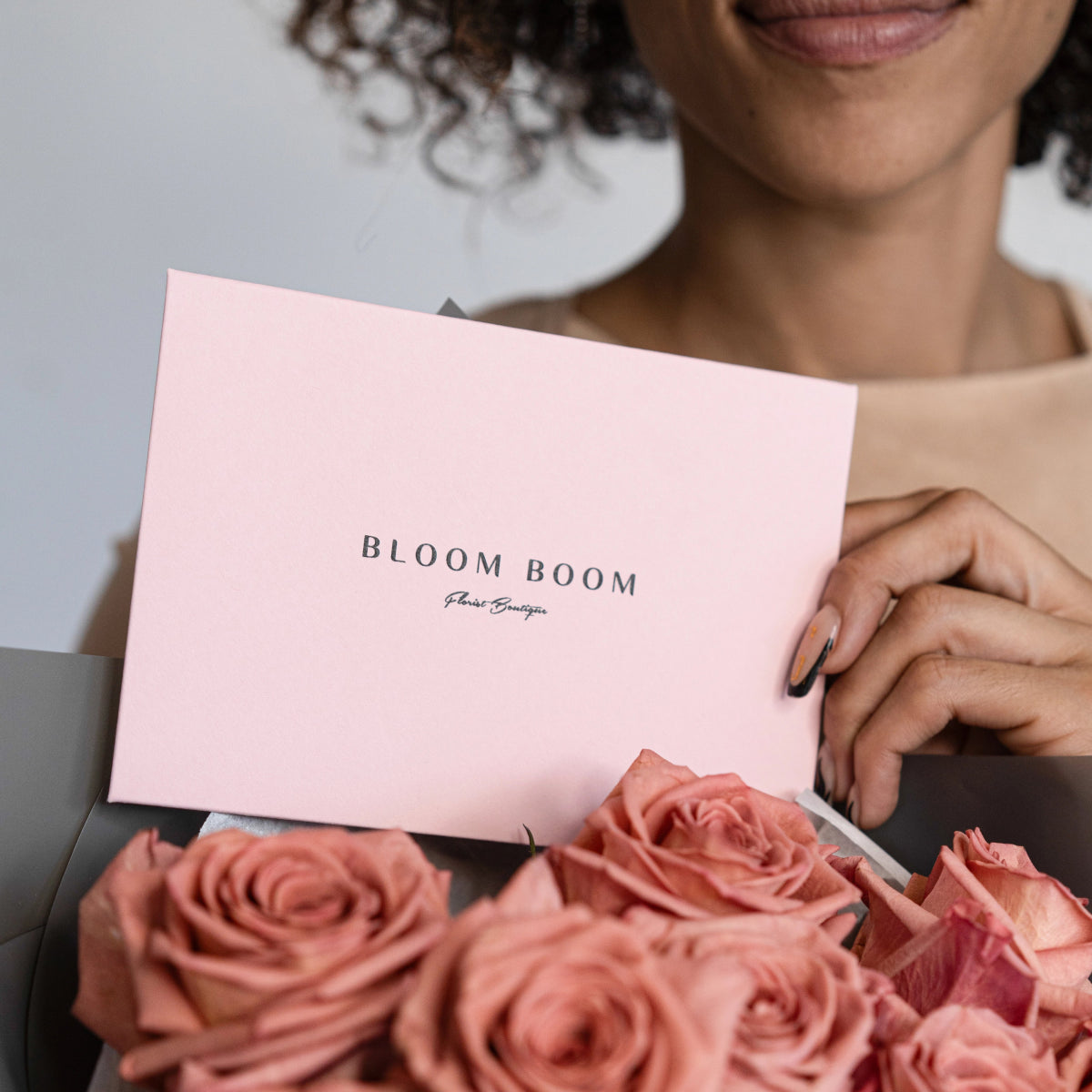 Woman holding pink Bloom Boom gift box with coral pink roses, elegant floral boutique packaging