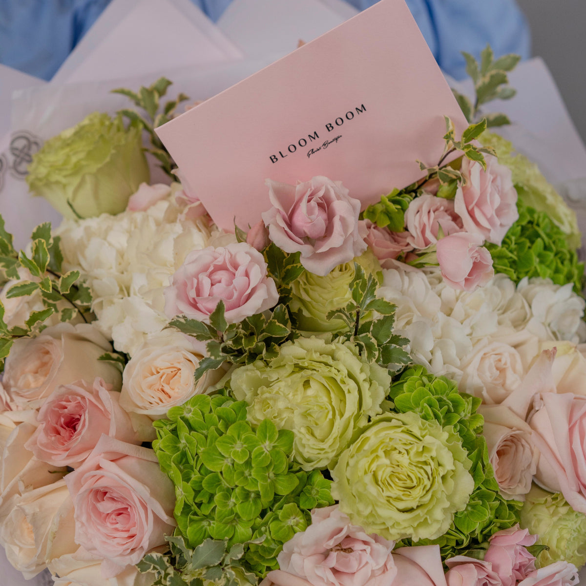 Bloom Boom luxury flower bouquet with pink roses, white ranunculus, green hydrangeas in soft paper wrapping