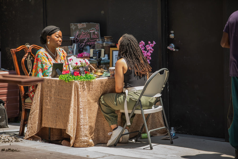 One-on-one tea lounge reading at a gold-draped table with fresh flowers on the patio