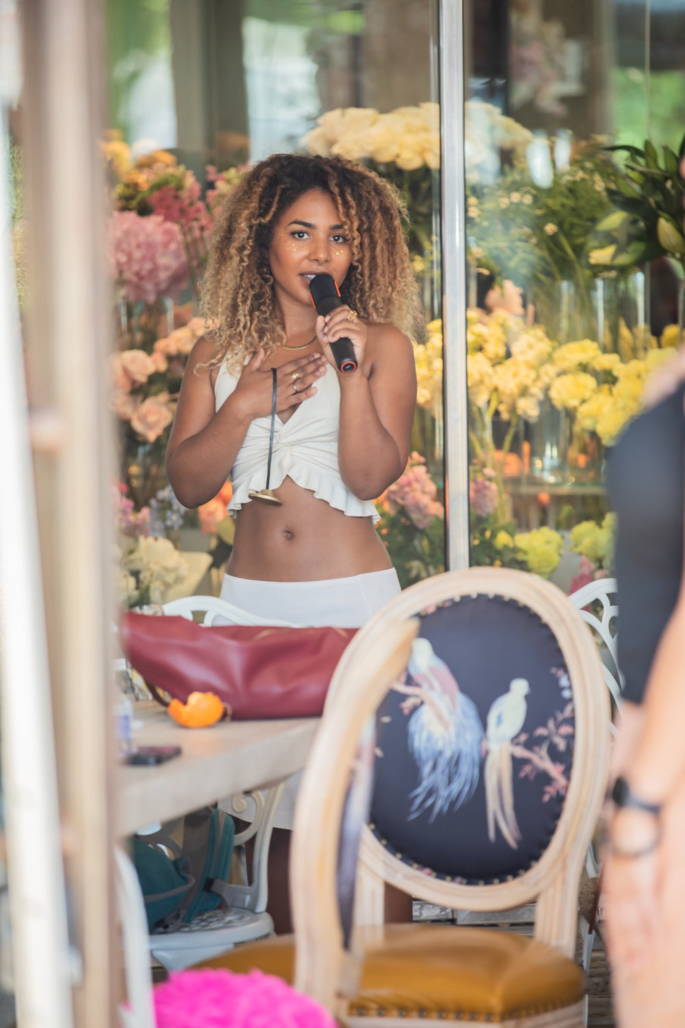 Vocalist performing in front of a wall of yellow and pink flower displays