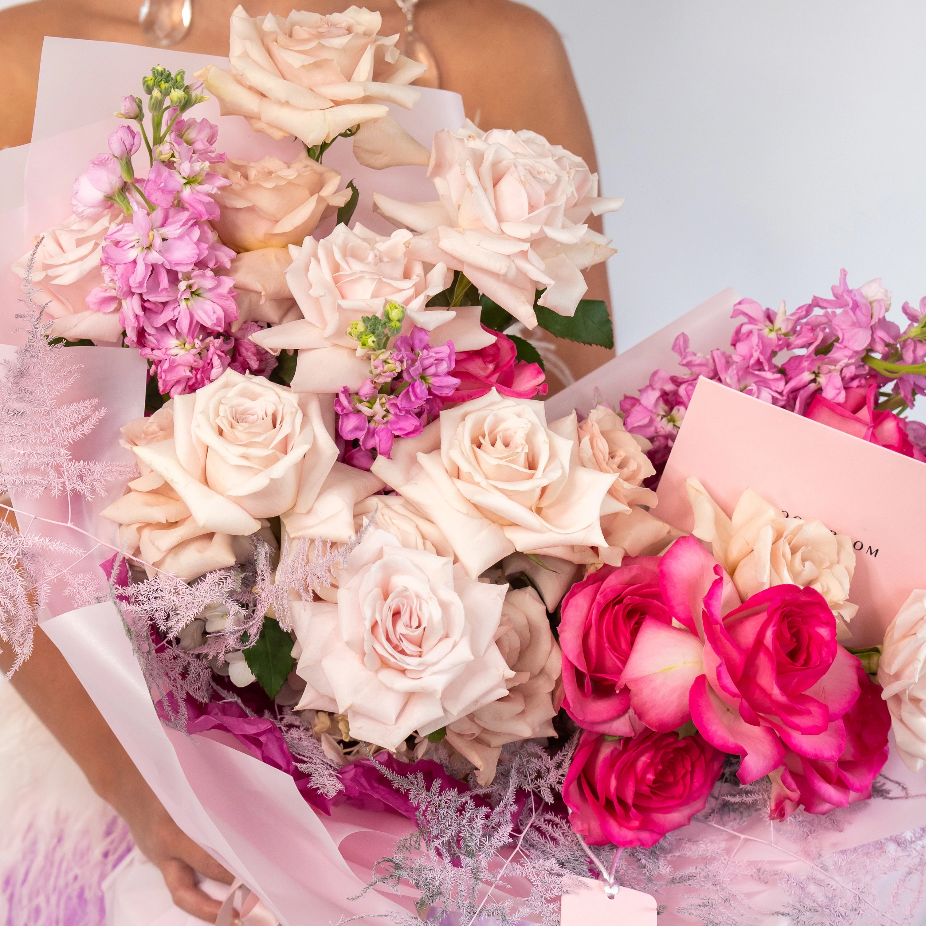 Blush pink roses and hot pink ranunculus bouquet with dusty miller wrapped in pink ribbon for flower delivery