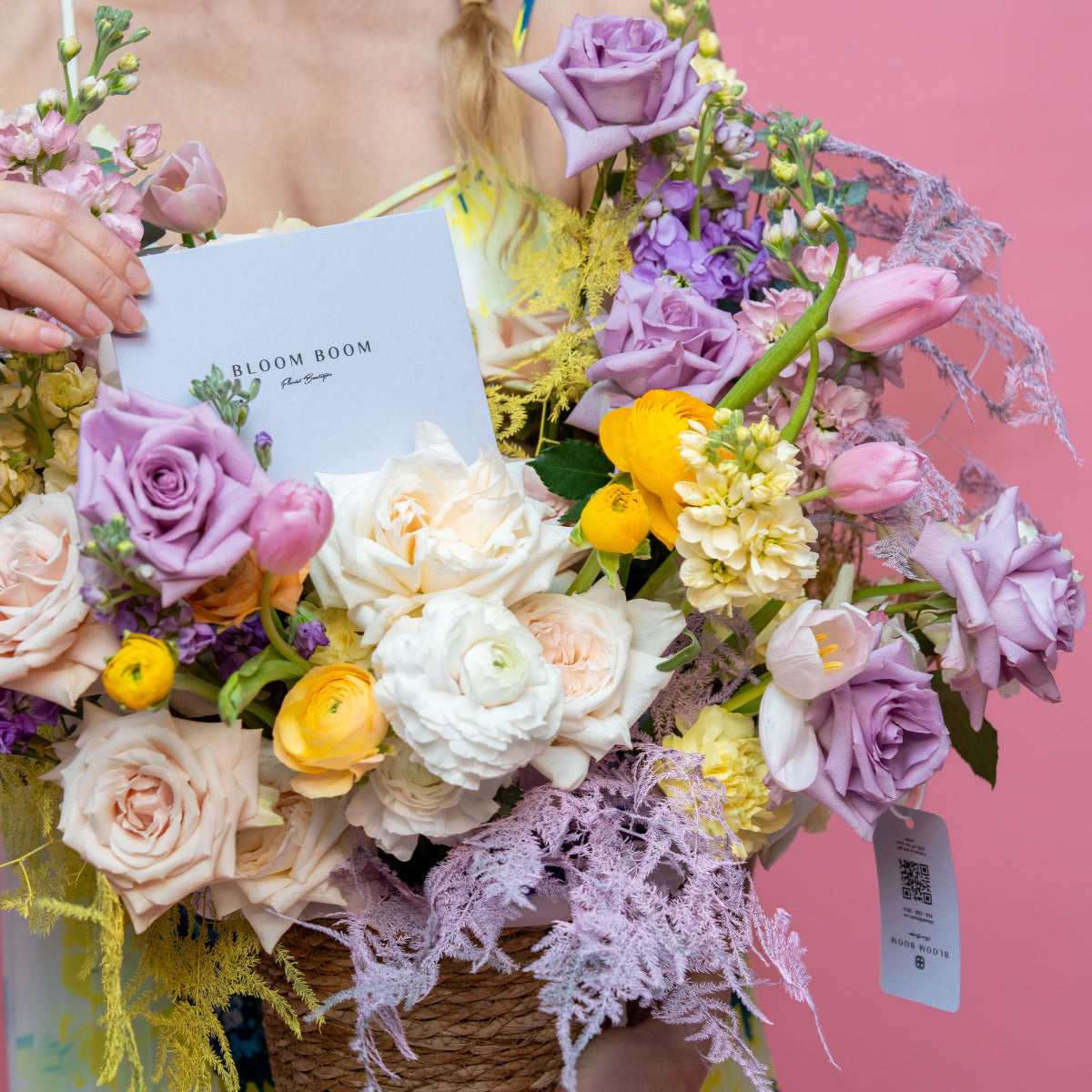 Mixed flower bouquet with lavender roses, white ranunculus, yellow flowers in wicker basket with lace trim