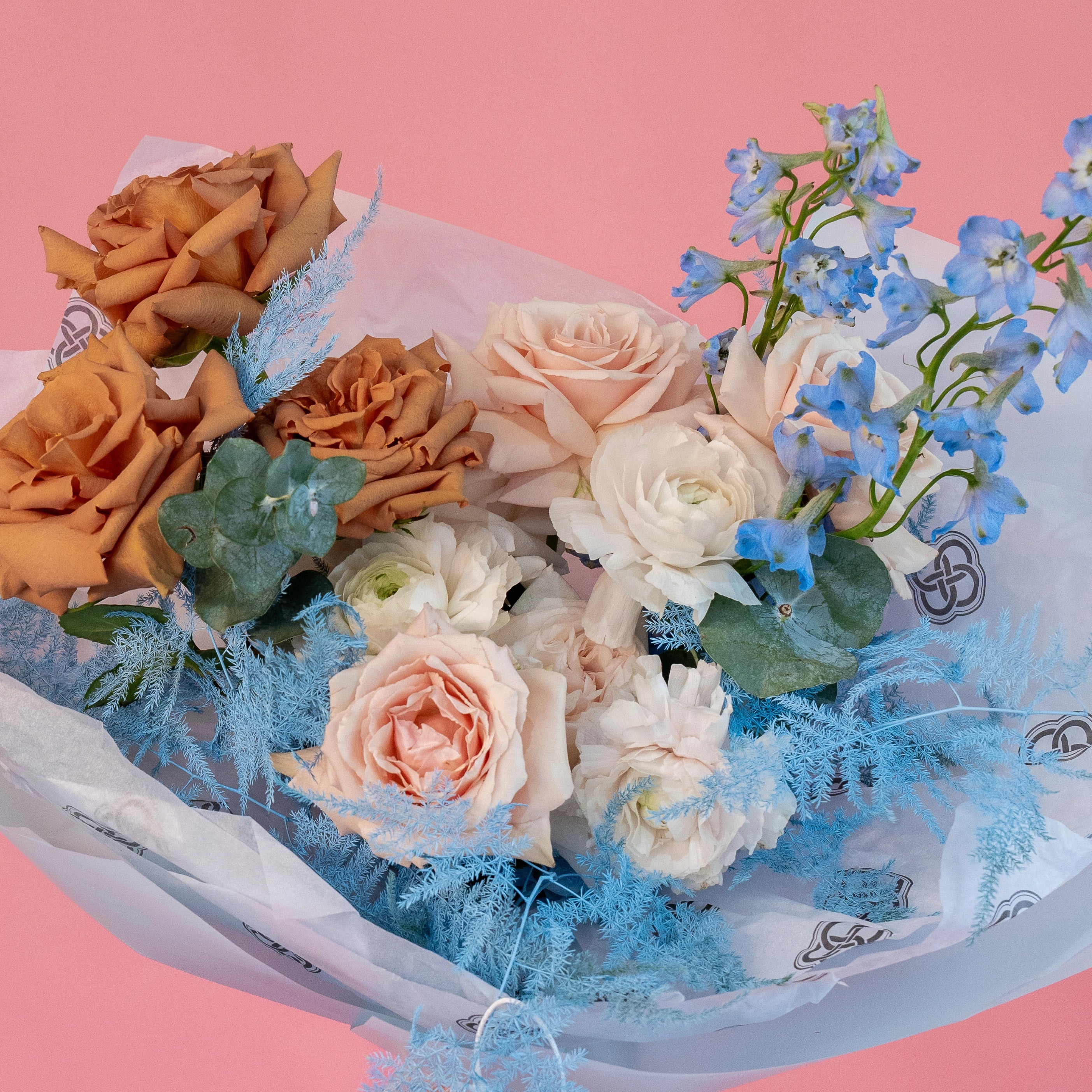 Cappuccino roses, blush pink roses, white ranunculus and blue delphinium mixed bouquet with dusty miller foliage