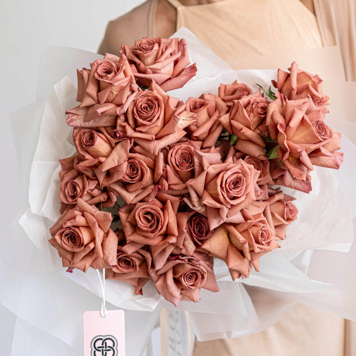Dusty rose bouquet with 25 premium roses wrapped in white tissue paper with brand tag