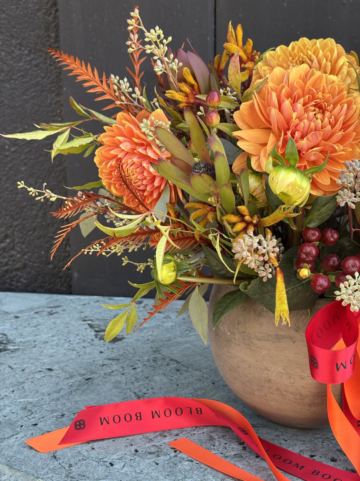 Side view of Ember Blooms with apricot dahlias, rust-tinted fern and seeded eucalyptus in a clay-toned ceramic pot