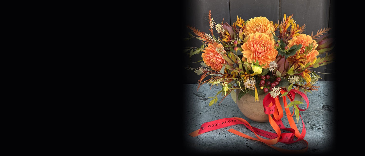 Ember Blooms fall arrangement of orange dahlias and kangaroo paw on the right of a black background