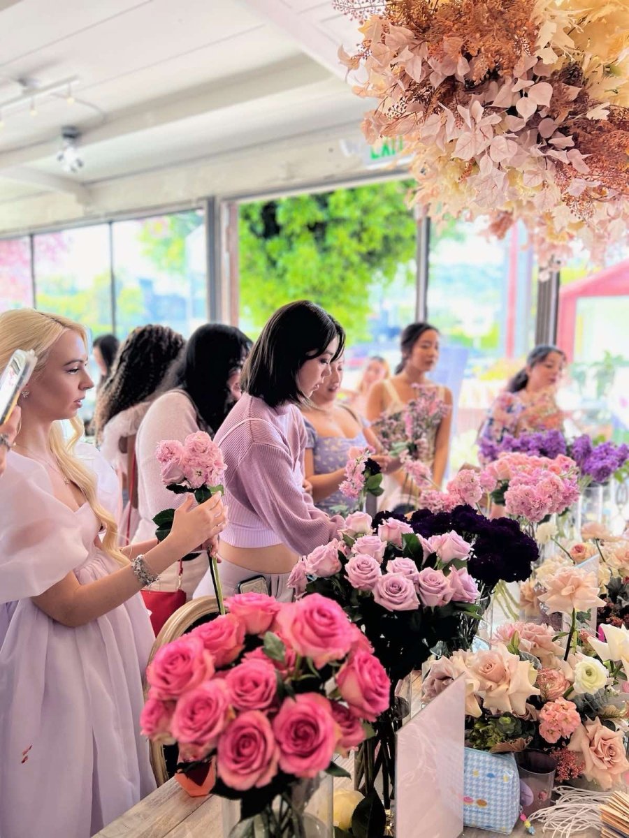 Women selecting colorful fresh roses and flowers at bright flower arranging workshop with pink, purple and coral blooms