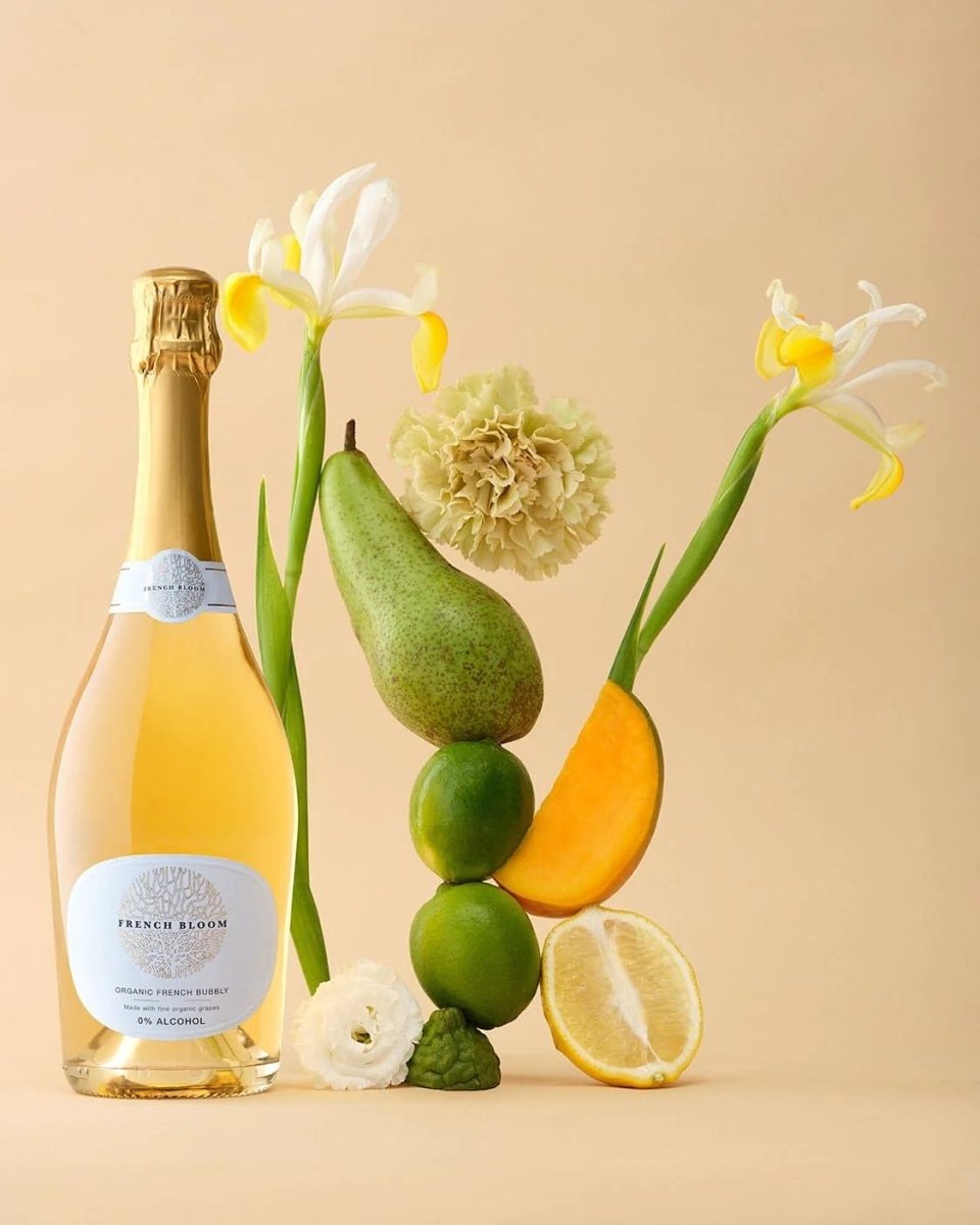 French Bloom organic bubbly bottle with artistic arrangement of white iris flowers, citrus fruits, and avocado