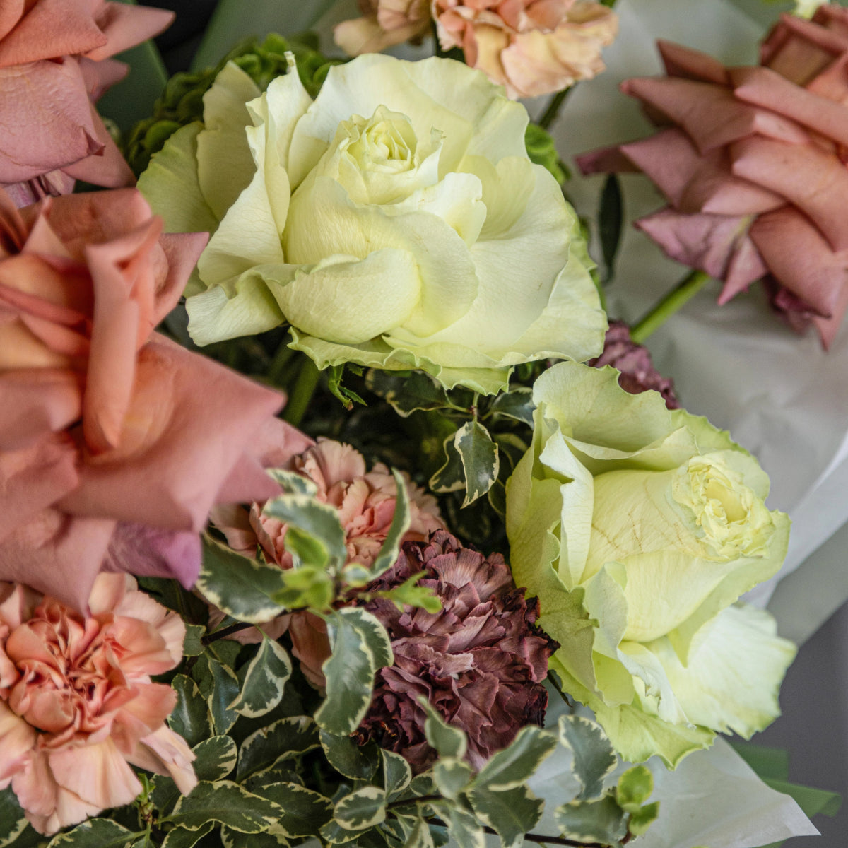 Mixed flower bouquet with cream roses, pink carnations, purple hydrangea and variegated foliage in soft pastel tones