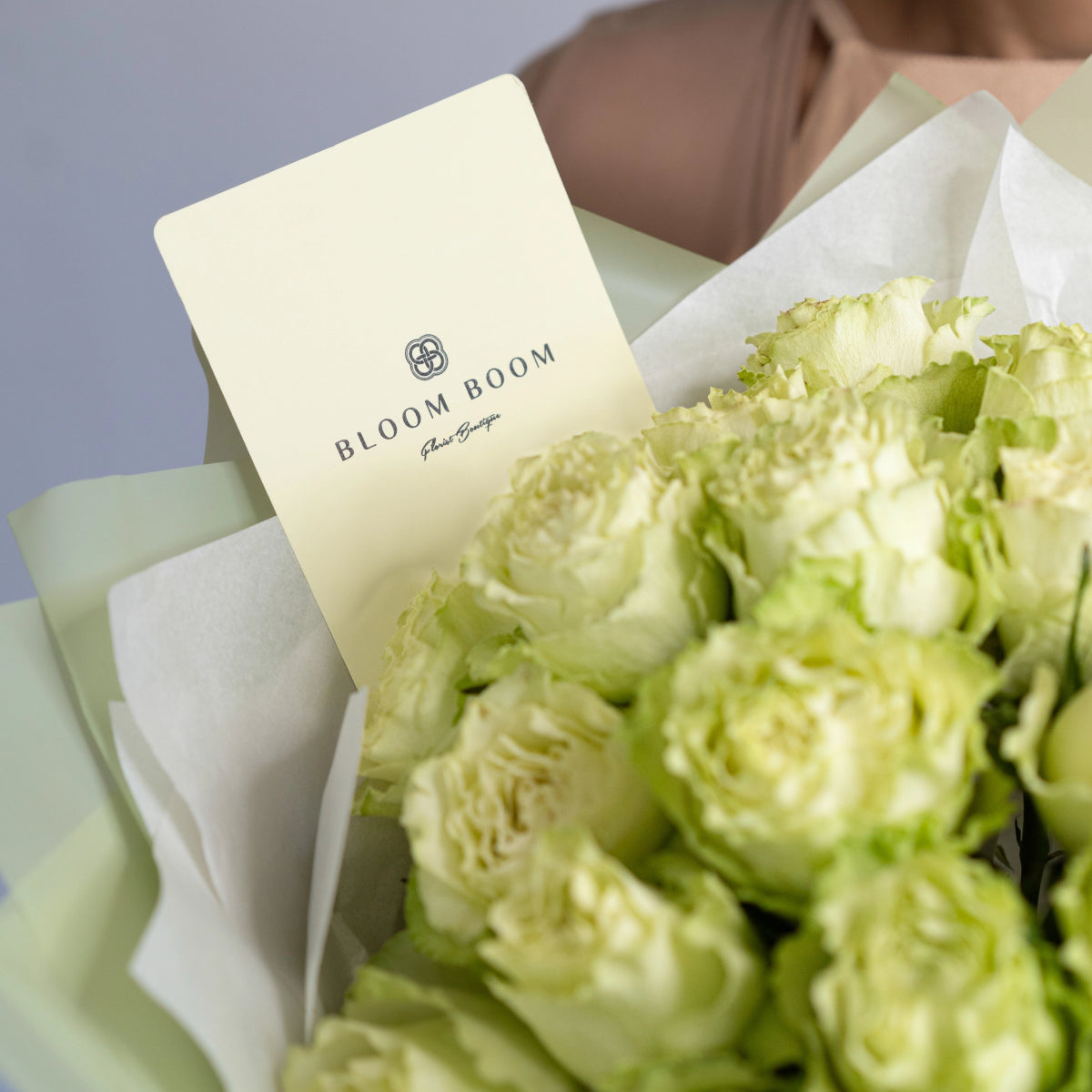 Light green roses bouquet wrapped in white tissue paper with sage green ribbon and Bloom Boom gift card