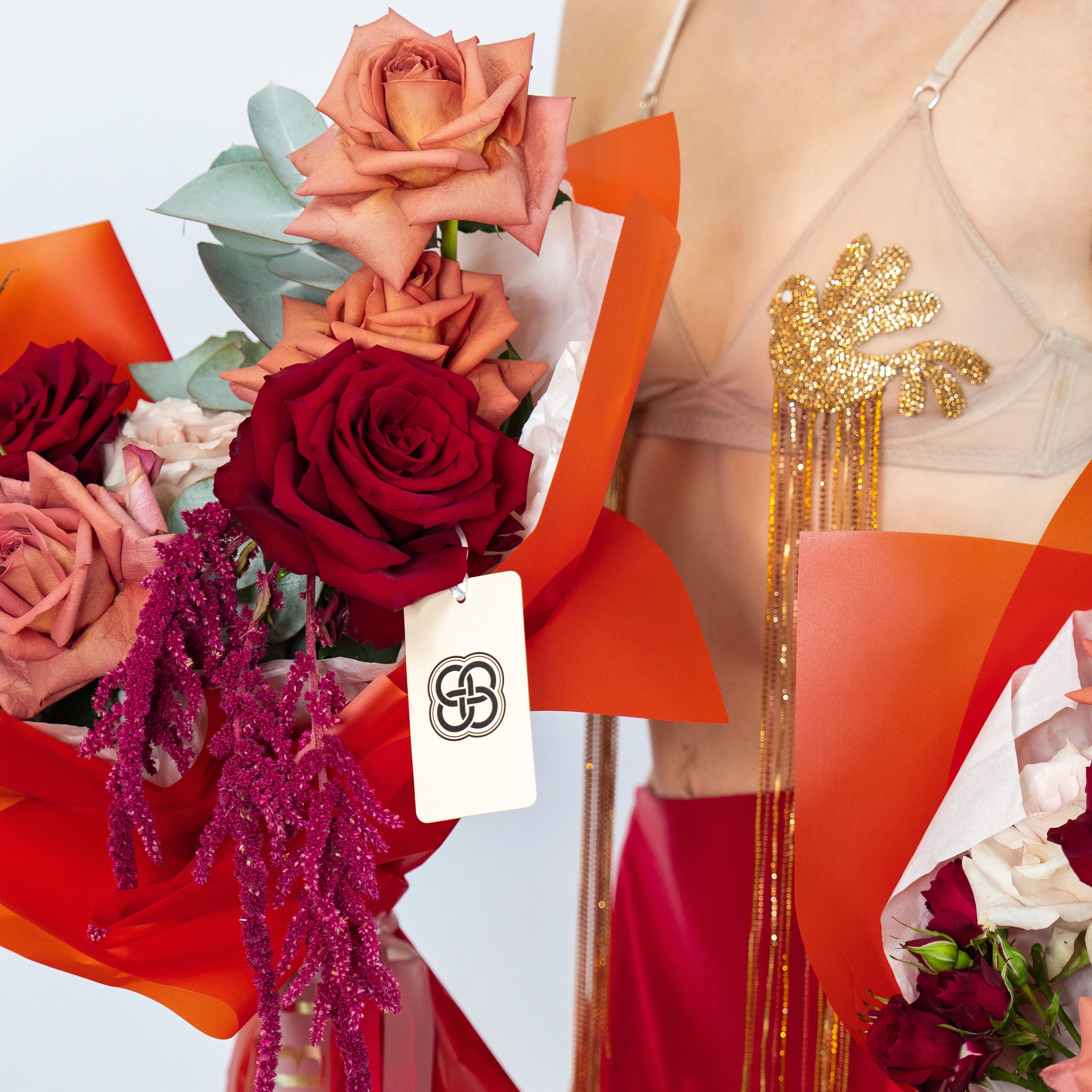 Mixed rose bouquet with burgundy and coral roses, eucalyptus leaves, purple dried flowers in orange wrapping paper