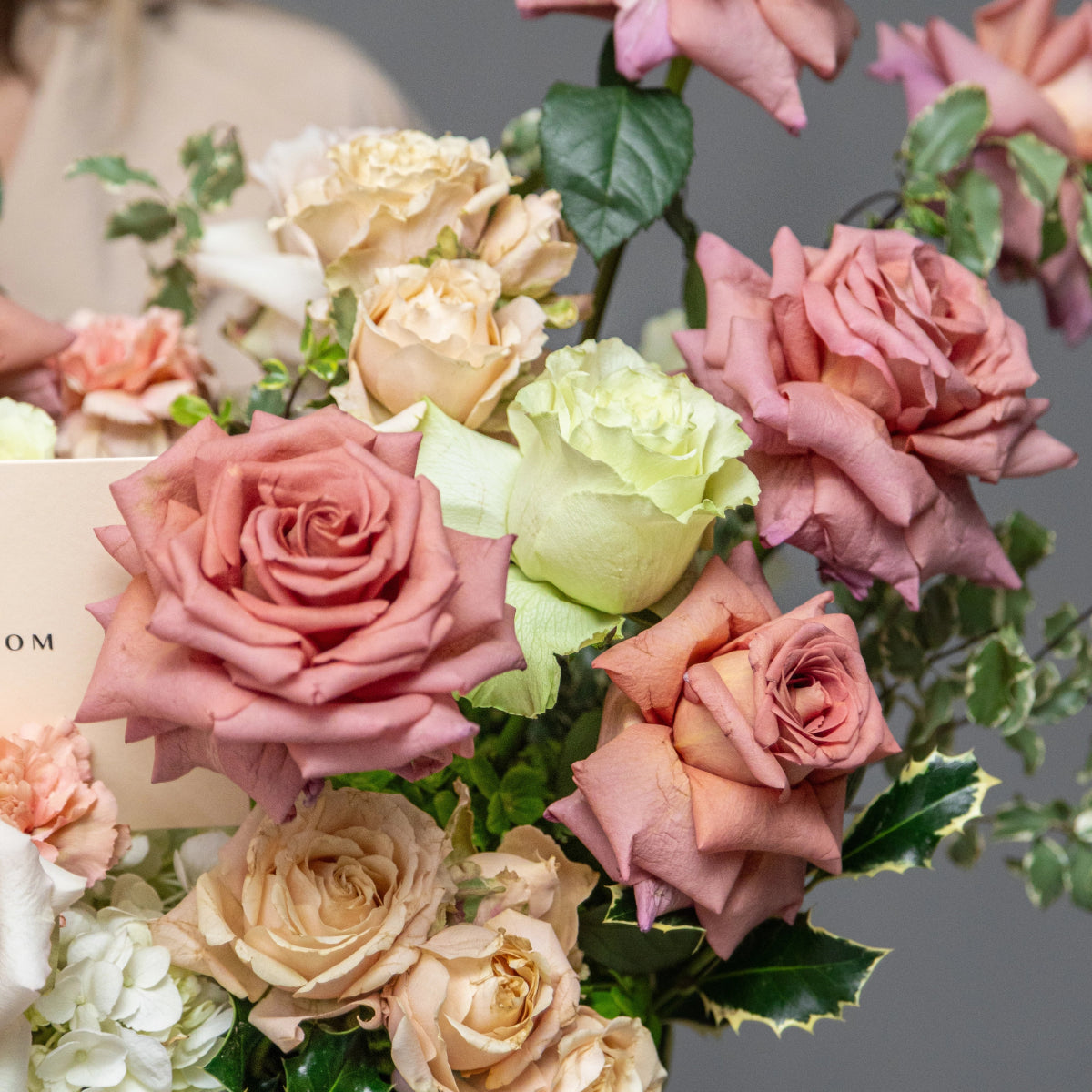 Mixed rose bouquet with pink, cream, and green roses plus white carnations and green foliage