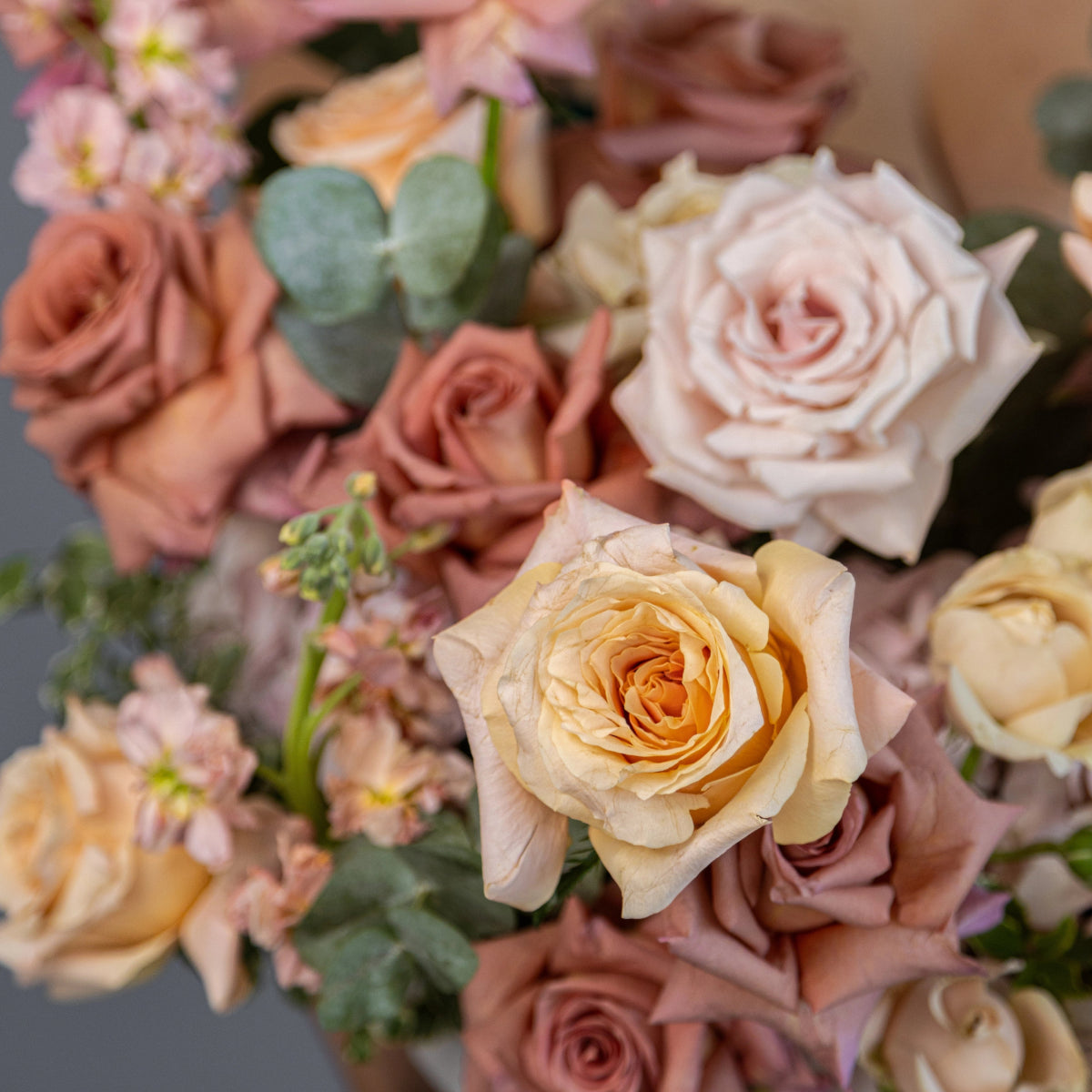 Pastel rose bouquet with blush pink, peach and cream roses mixed with eucalyptus leaves in soft romantic arrangement