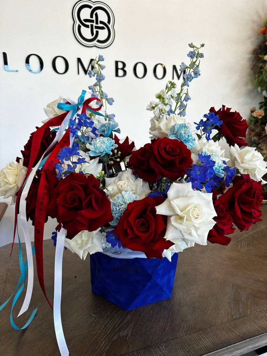 Patriotic flower bouquet with deep red roses, white roses, blue delphiniums in royal blue velvet box with ribbons