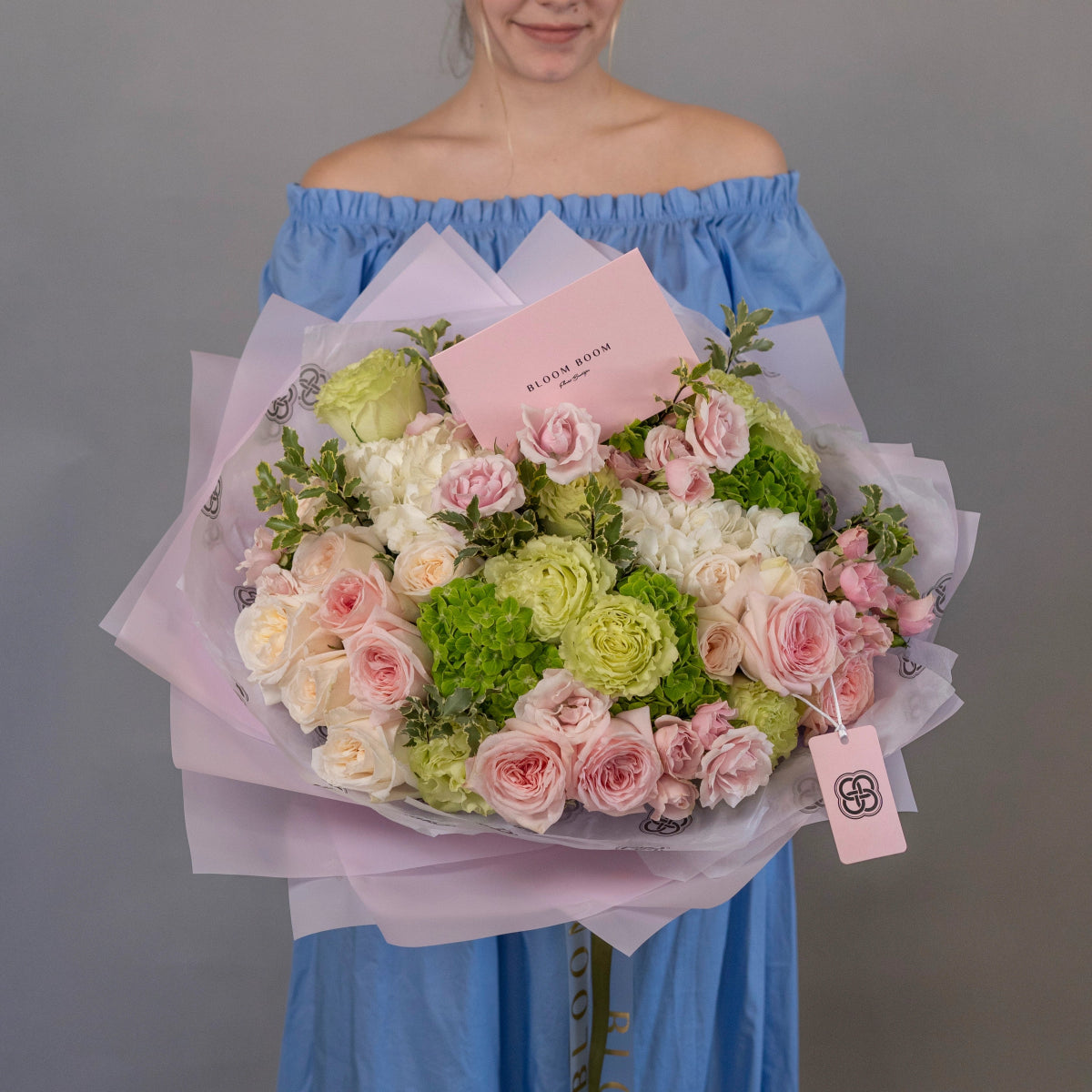 Large mixed flower bouquet with pink roses, green hydrangeas, white blooms wrapped in pink tissue paper