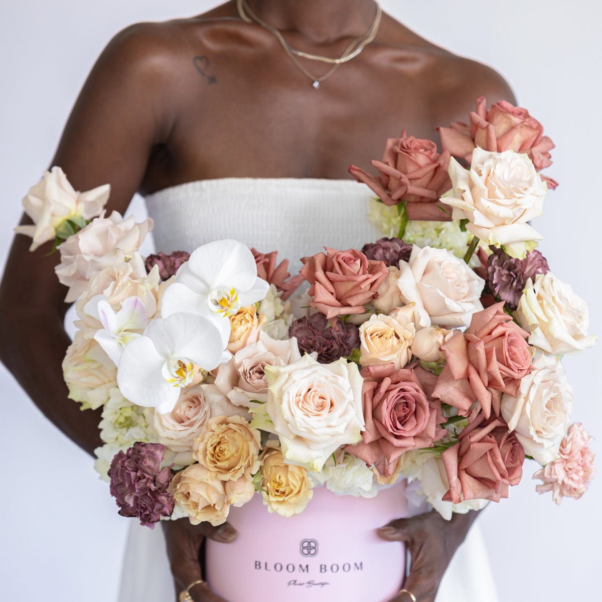 Luxurious pink flower box with blush roses, white orchids, and burgundy carnations in elegant arrangement