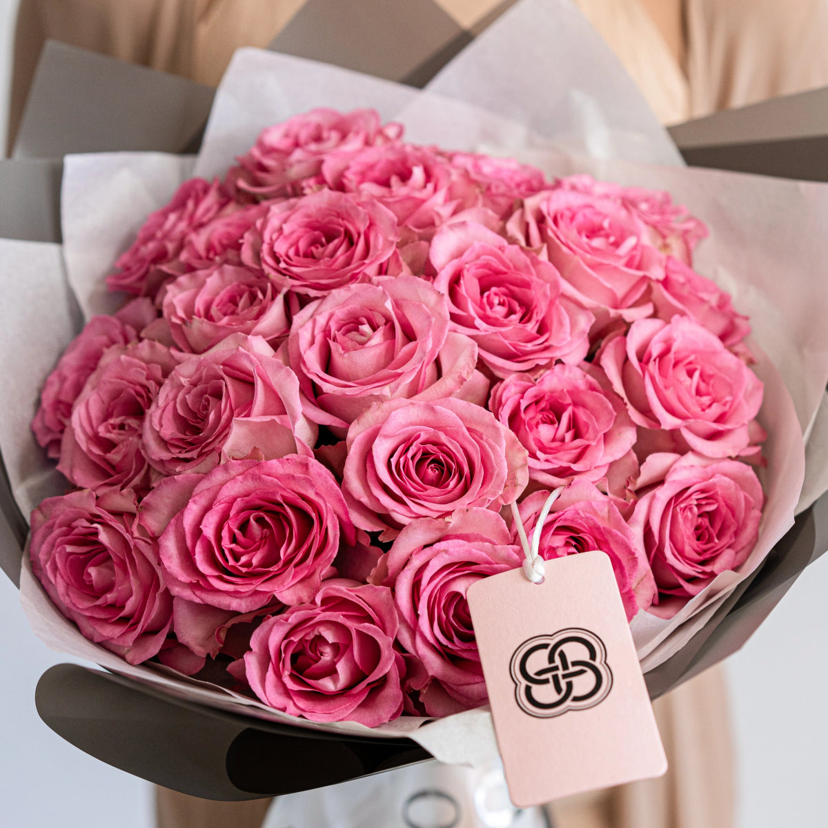 Pink rose bouquet wrapped in white tissue paper with branded tag, featuring 25 fresh Martina roses in soft blush tones