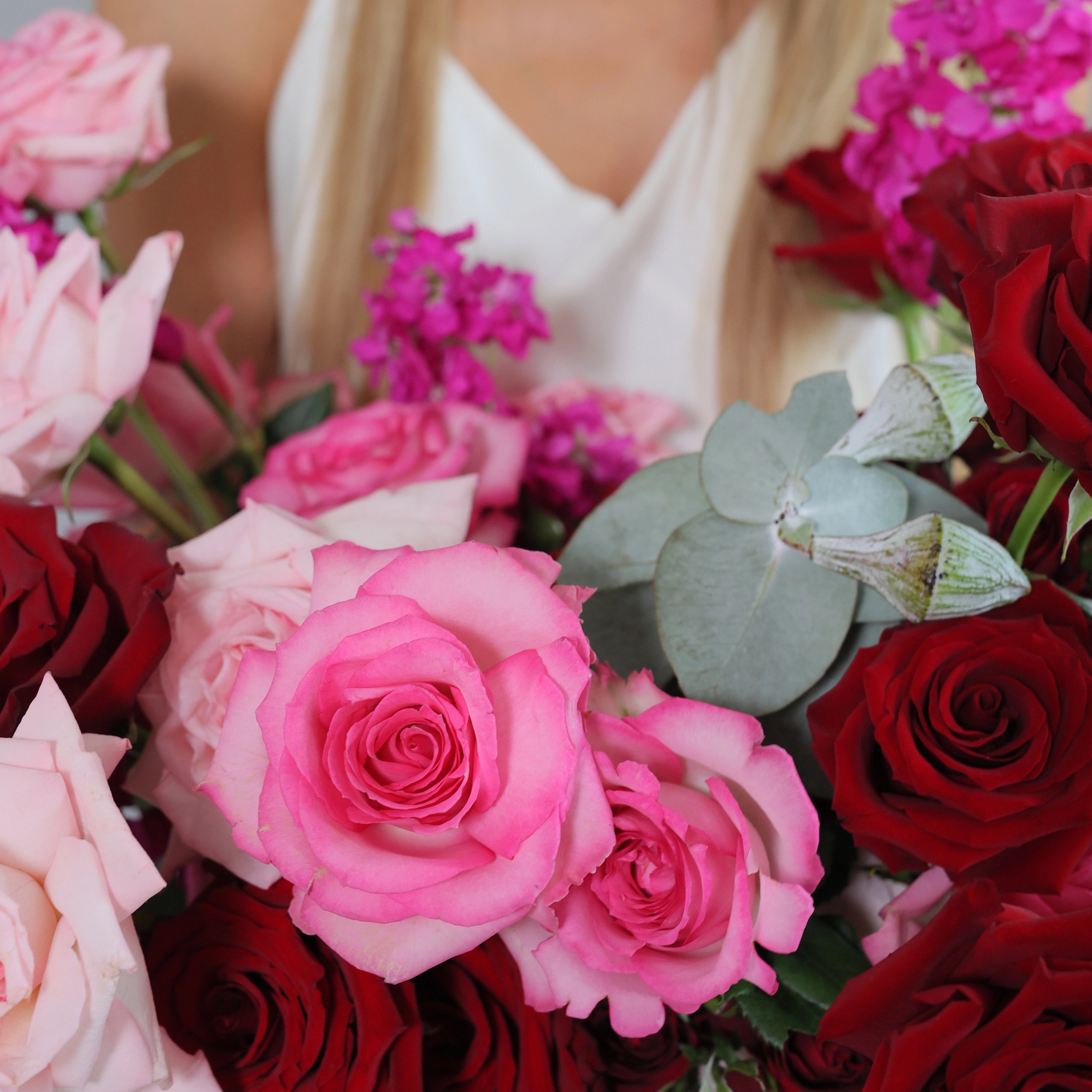 Mixed rose bouquet with pink, red, and blush roses accented with eucalyptus leaves held by woman in Los Angeles